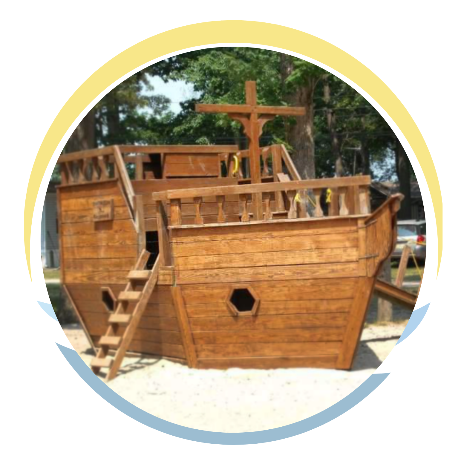 A wooden pirate ship play structure outdoors with trees in the background.