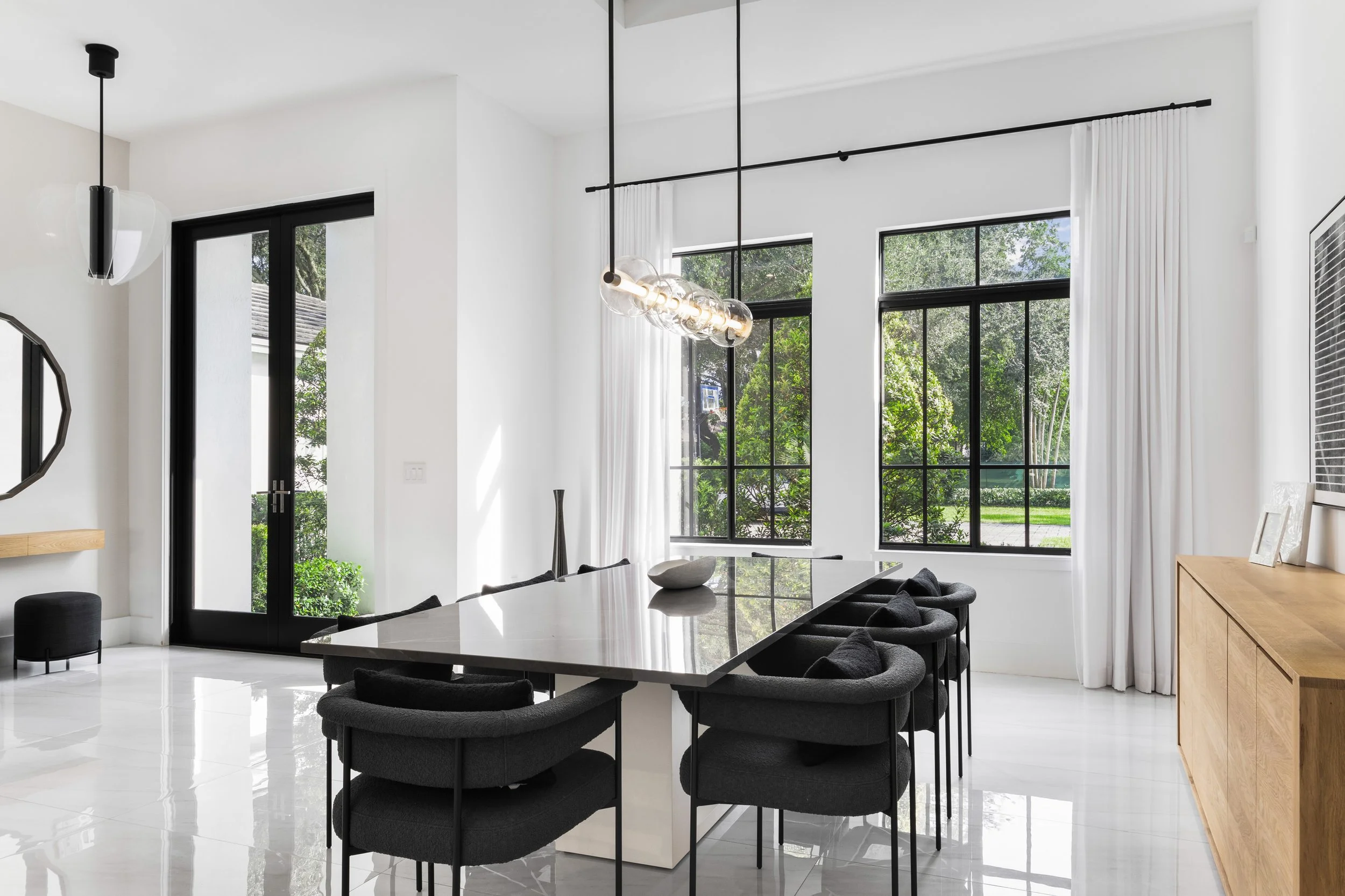 Contemporary dining space with dark accent chairs - Modern Family Estate - Pinecrest - CURATED. Studio