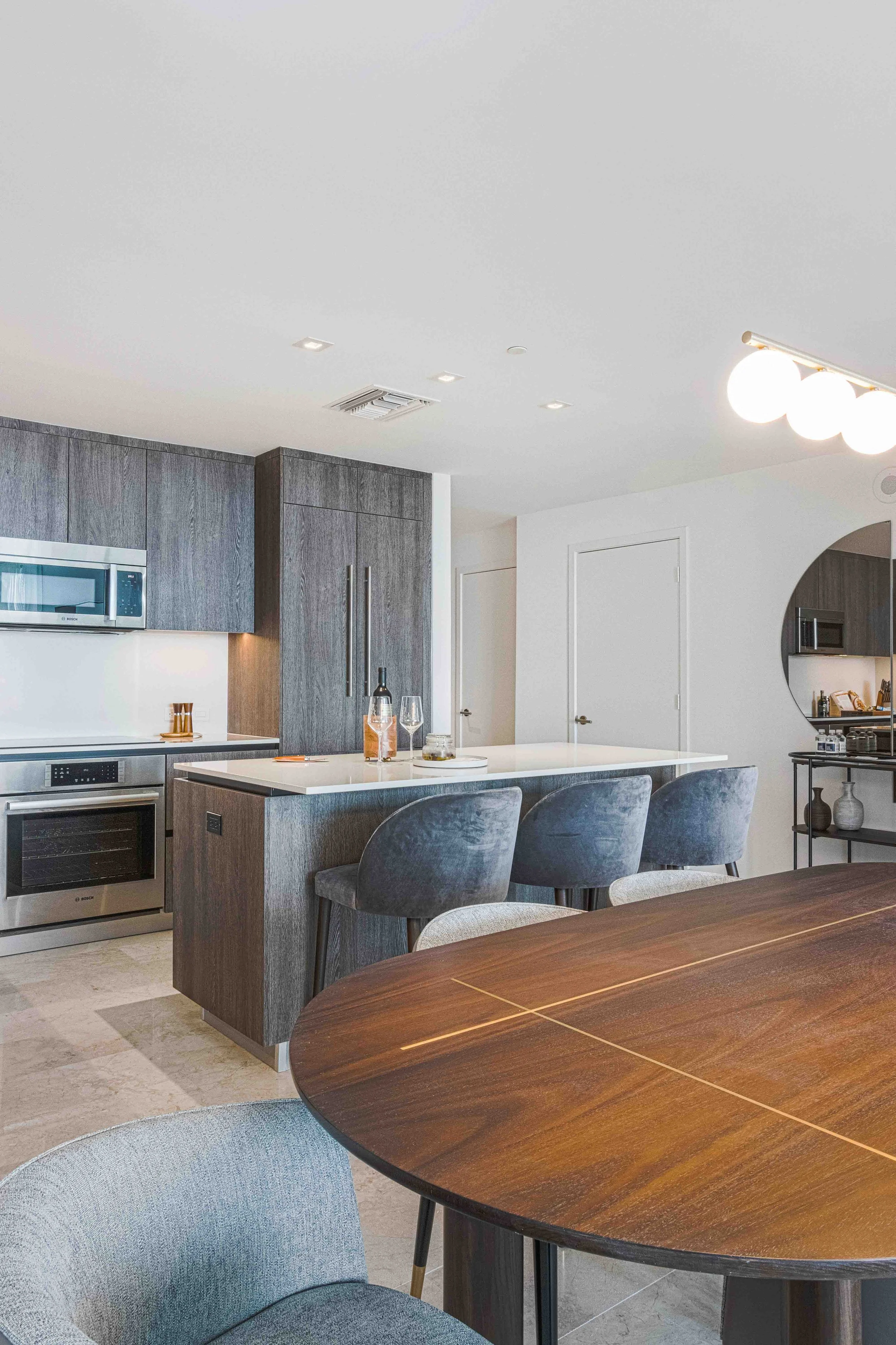 Modern kitchen with gray wood cabinetry, white quartz island, and blue velvet counter stools at Rise Brickell City Centre in Miami, Interior Design by CURATED.