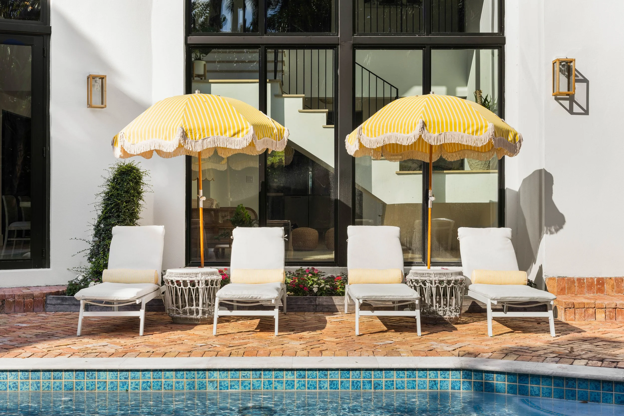 Outdoor pool area with lounge chairs and yellow umbrellas - Coastal Boho Estate - Coconut Grove - CURATED. Studio