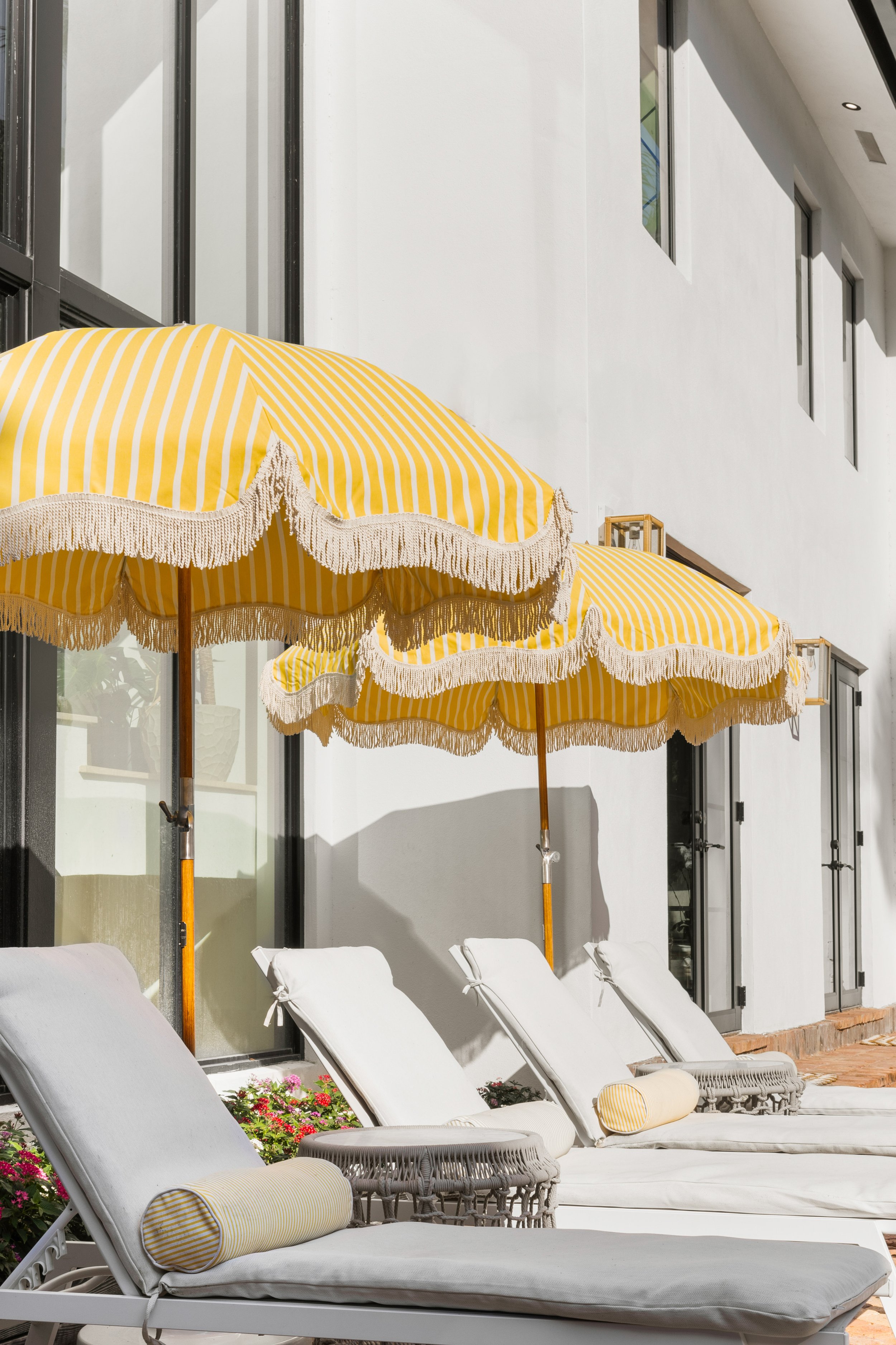 Sun loungers with bright yellow stripped umbrellas - Coastal Boho Estate - Coconut Grove - CURATED. Studio