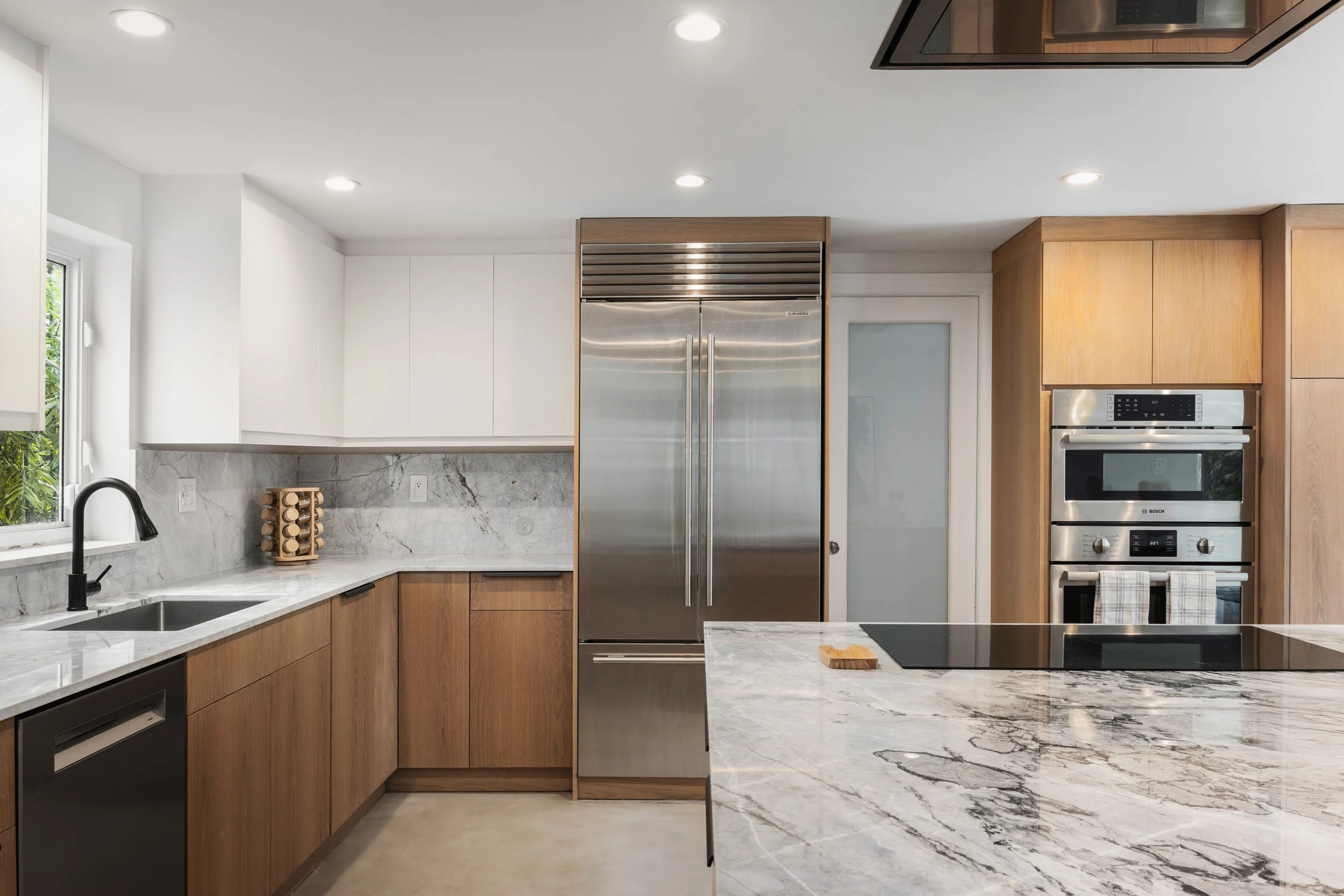 Modern kitchen with white cabinets and warm wood paneling - Modernized Brutalist Architecture - Coconut Grove - CURATED. Studio
