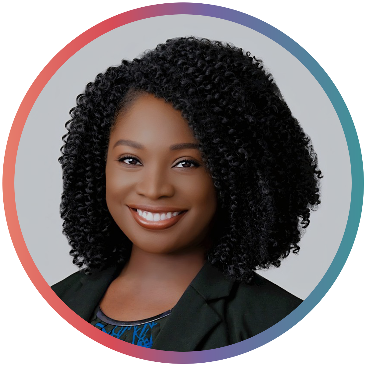 Portrait of a smiling African American woman with curly black hair, wearing a black blazer and a patterned top.