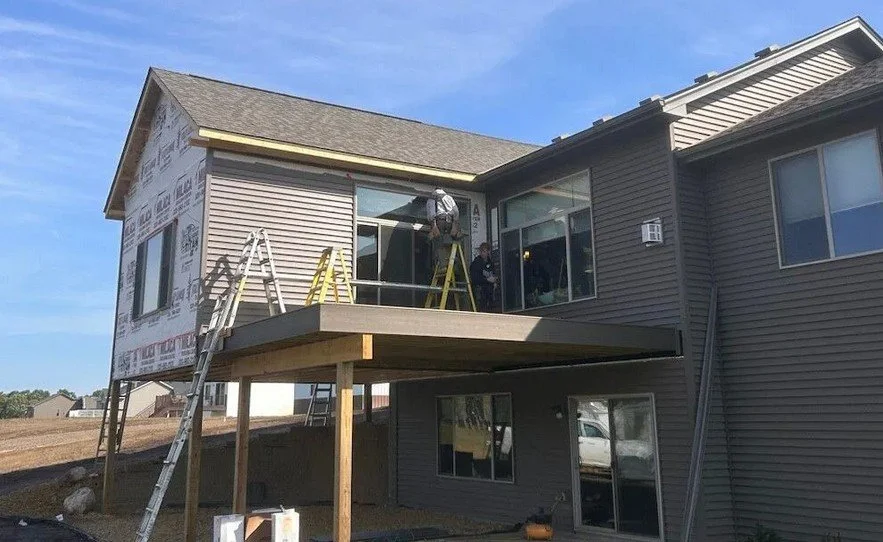 Scenic landscape with a lake in the foreground, rolling green hills, and tall mountains in the background under a cloudy sky.