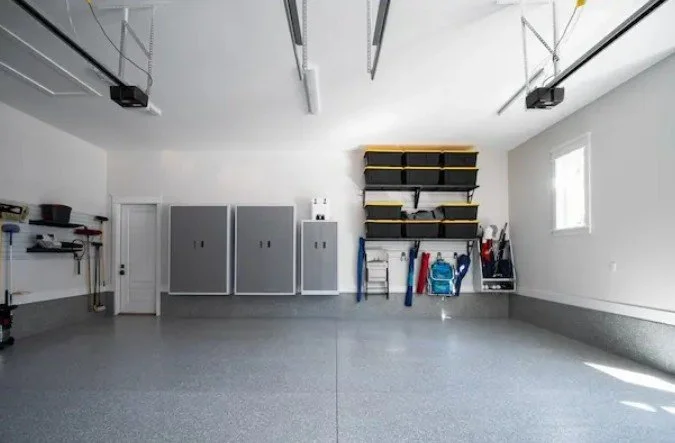 Mountains with snow caps, a green hillside, and a modern house with wooden and stone exterior in a remote landscape.