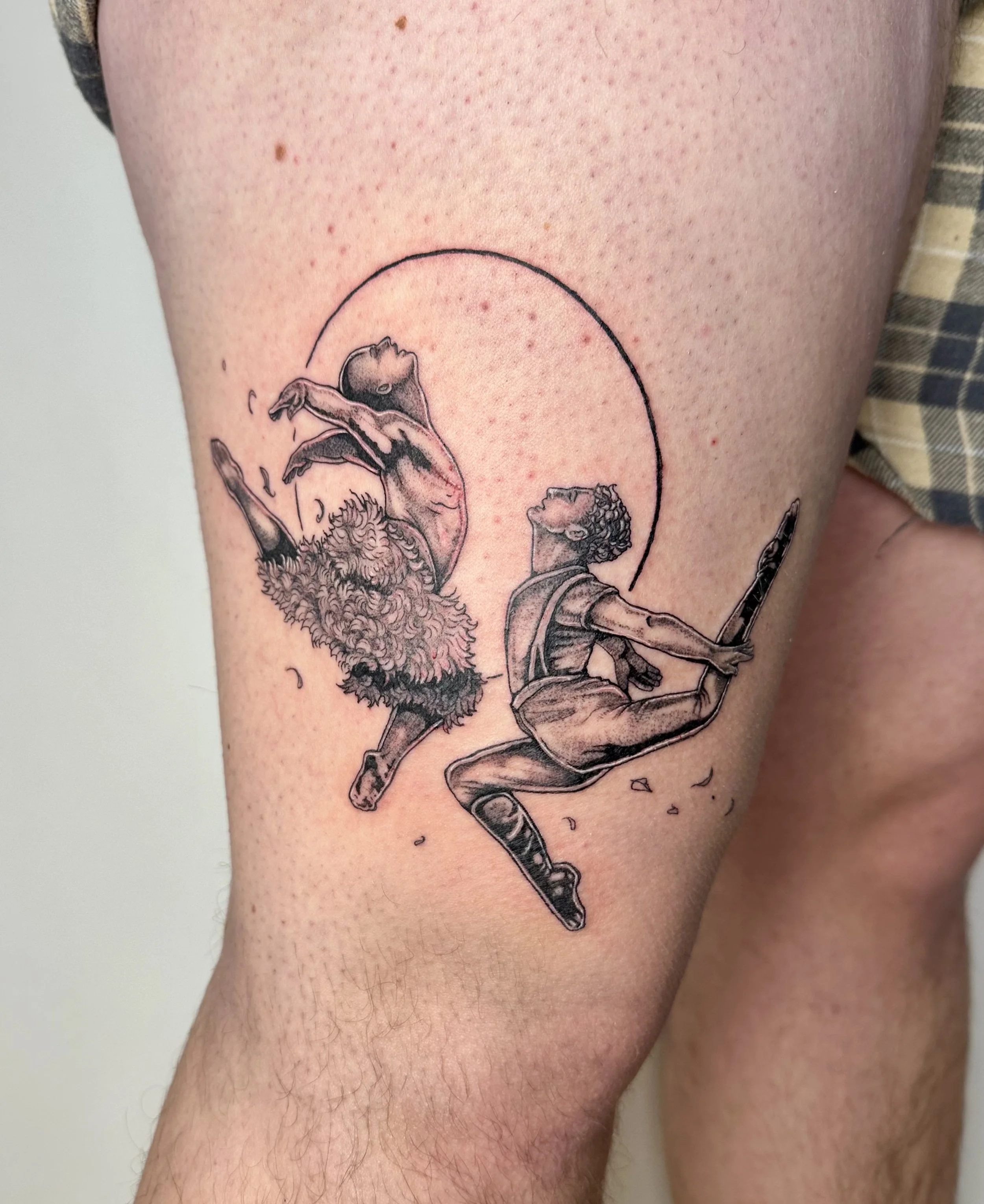 Tattoo of two figures from the ballet swan lake dancing, with a circle in the background, on a person's thigh.