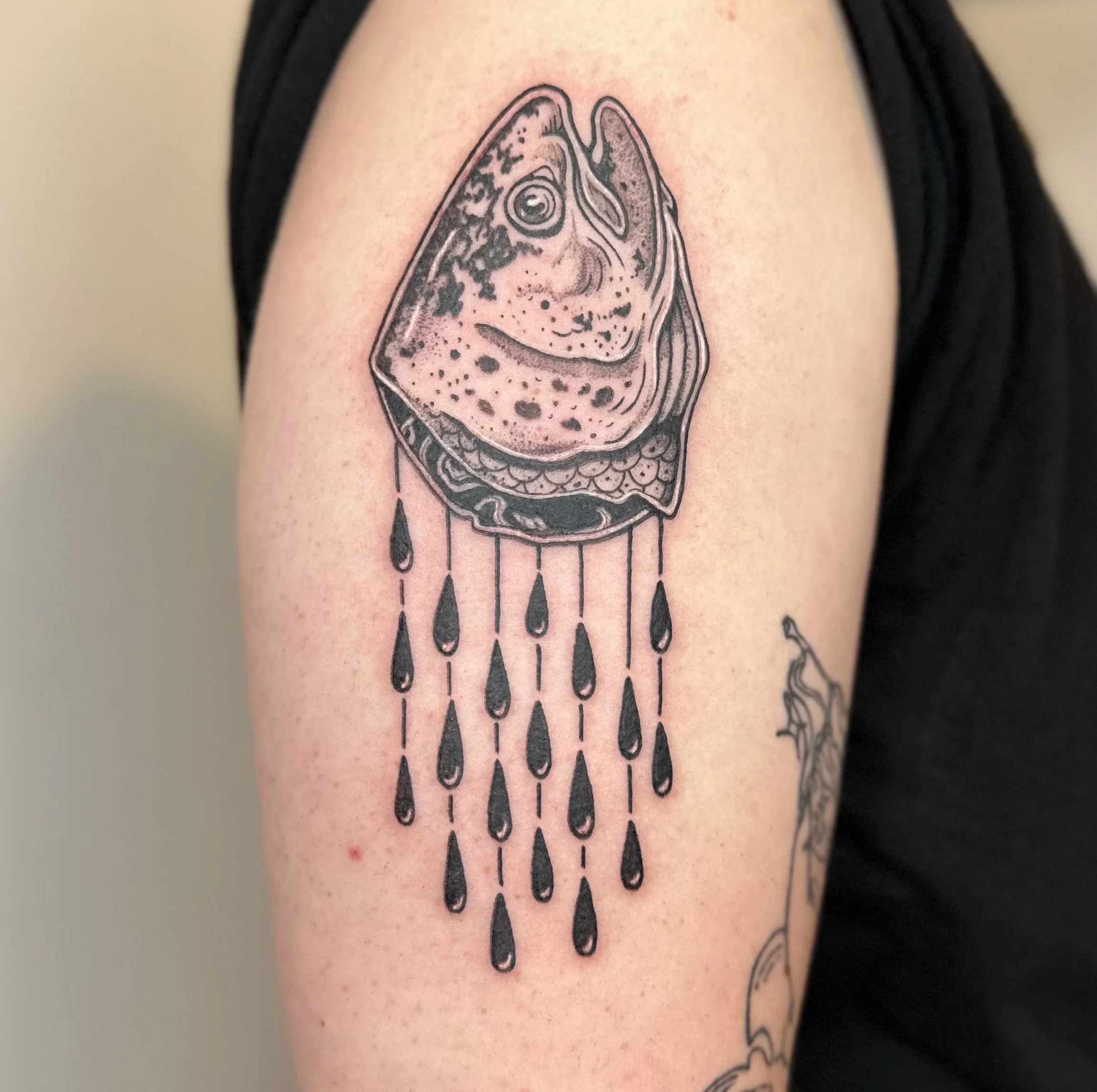 Tattoo of a fish with artistic black drops and lines hanging below.