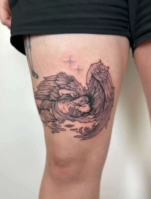 Tattoo of a transmasculine rendition of cupid waking up, on a person's upper thigh. The tattoo features detailed line work and shading.