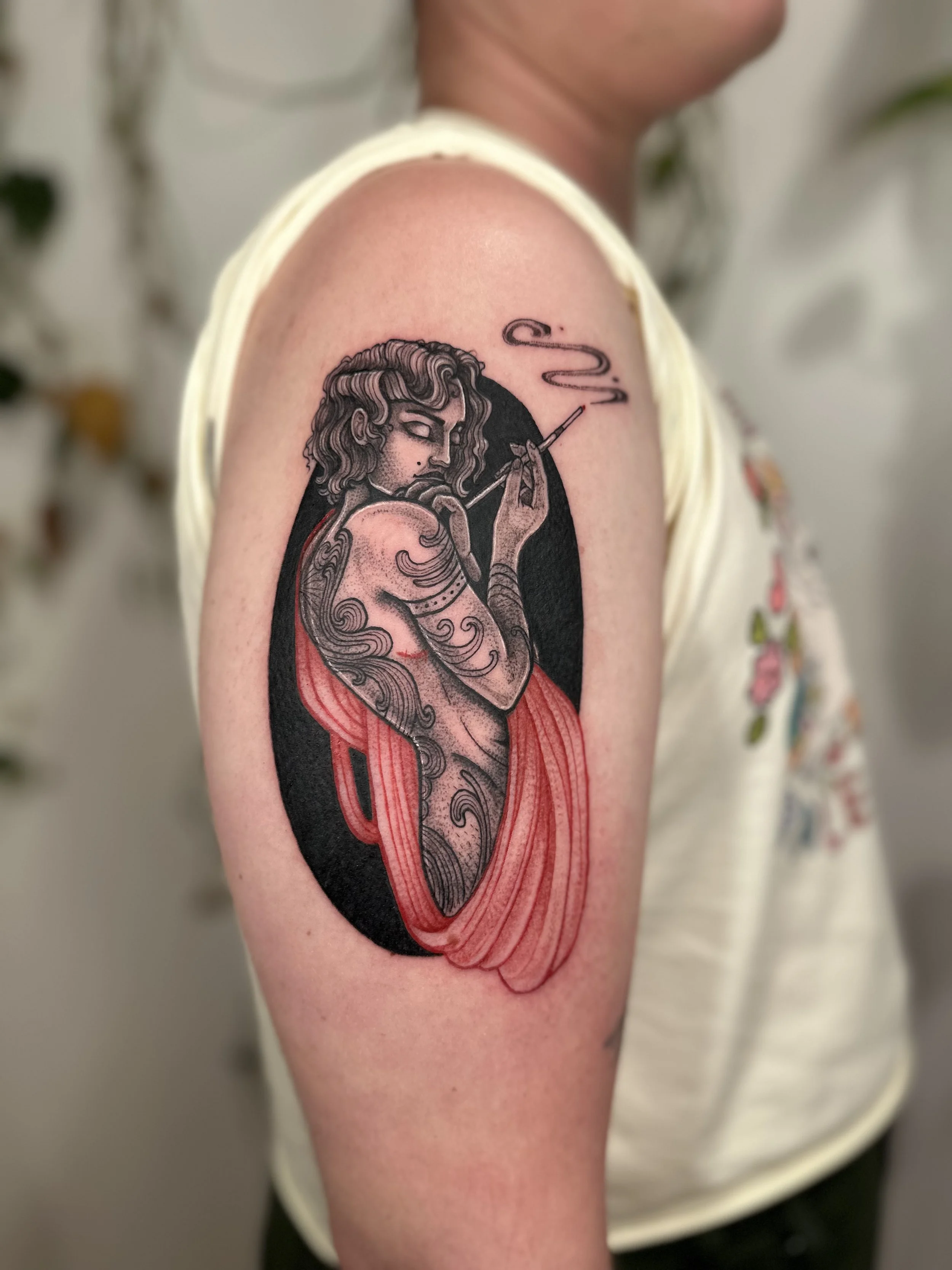 Tattoo of a woman with curly hair holding an cigarette, with a dark background and a red cloth draped around her body.