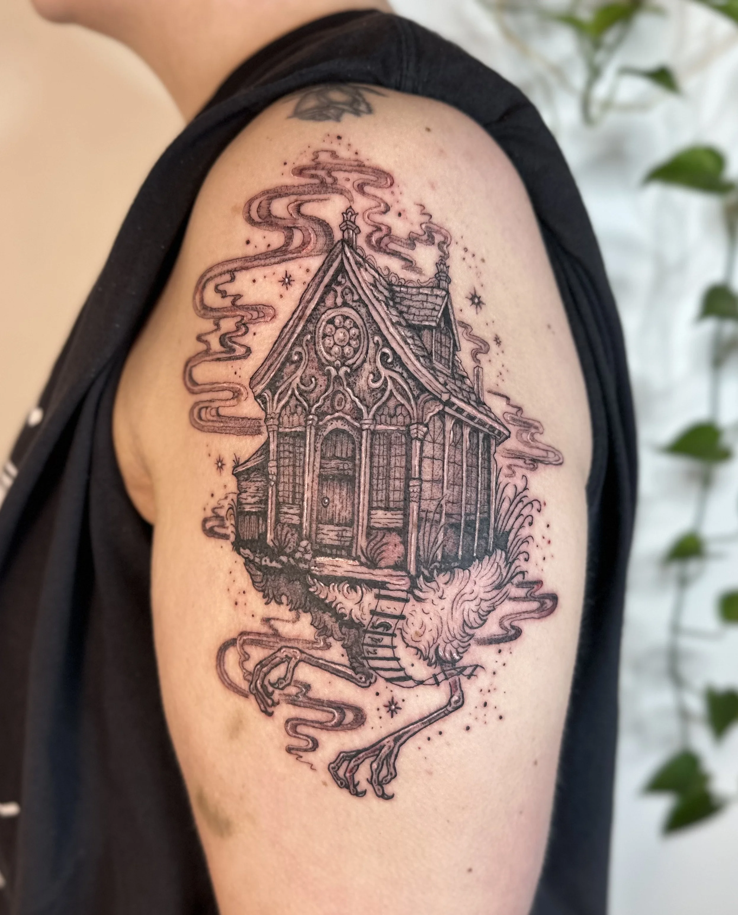 Tattoo of a floating haunted house with smoke and a horse's head on a long neck under stars.