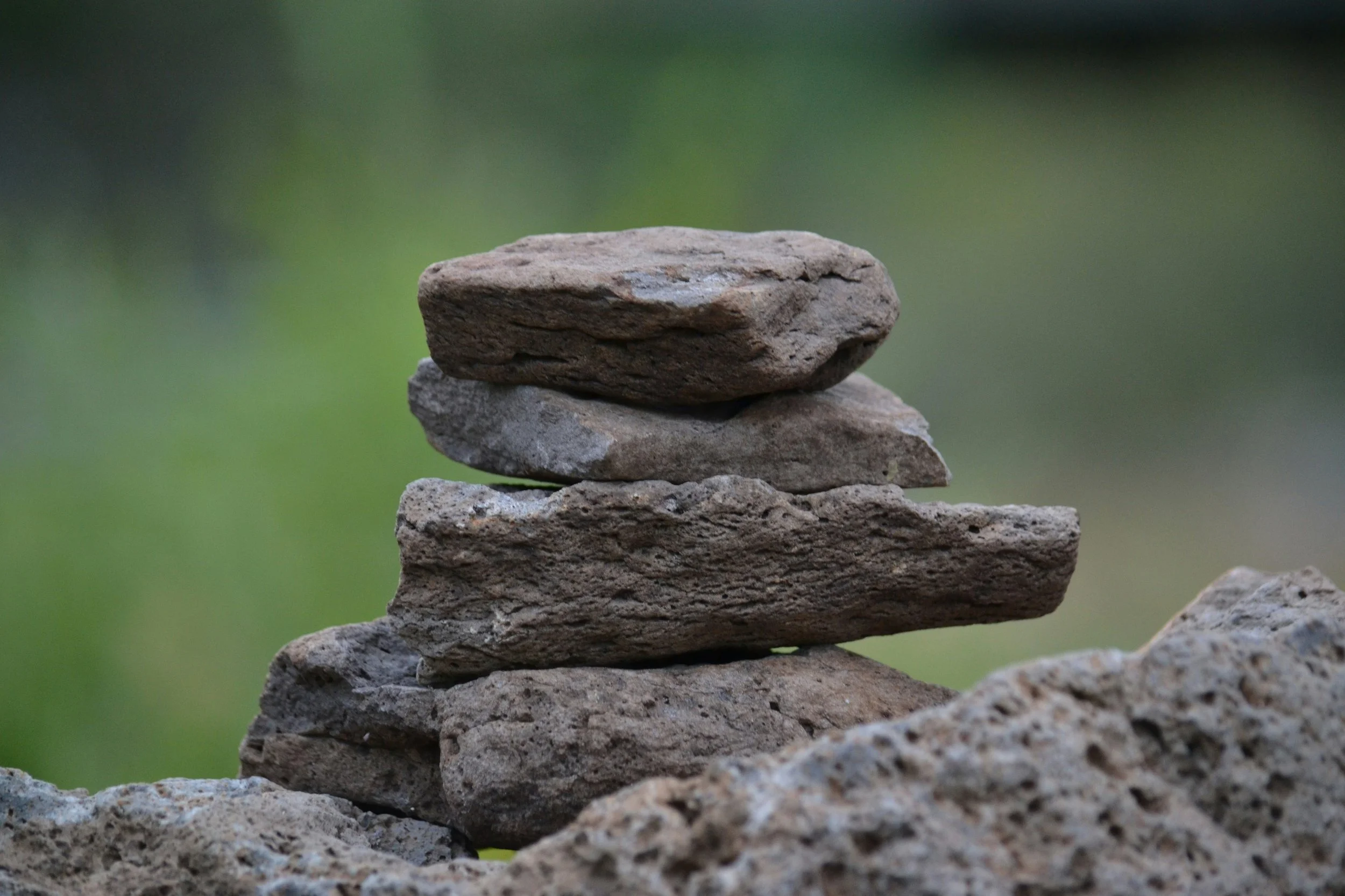 Stacked rocks on a natural outdoor surface with a blurred green background.