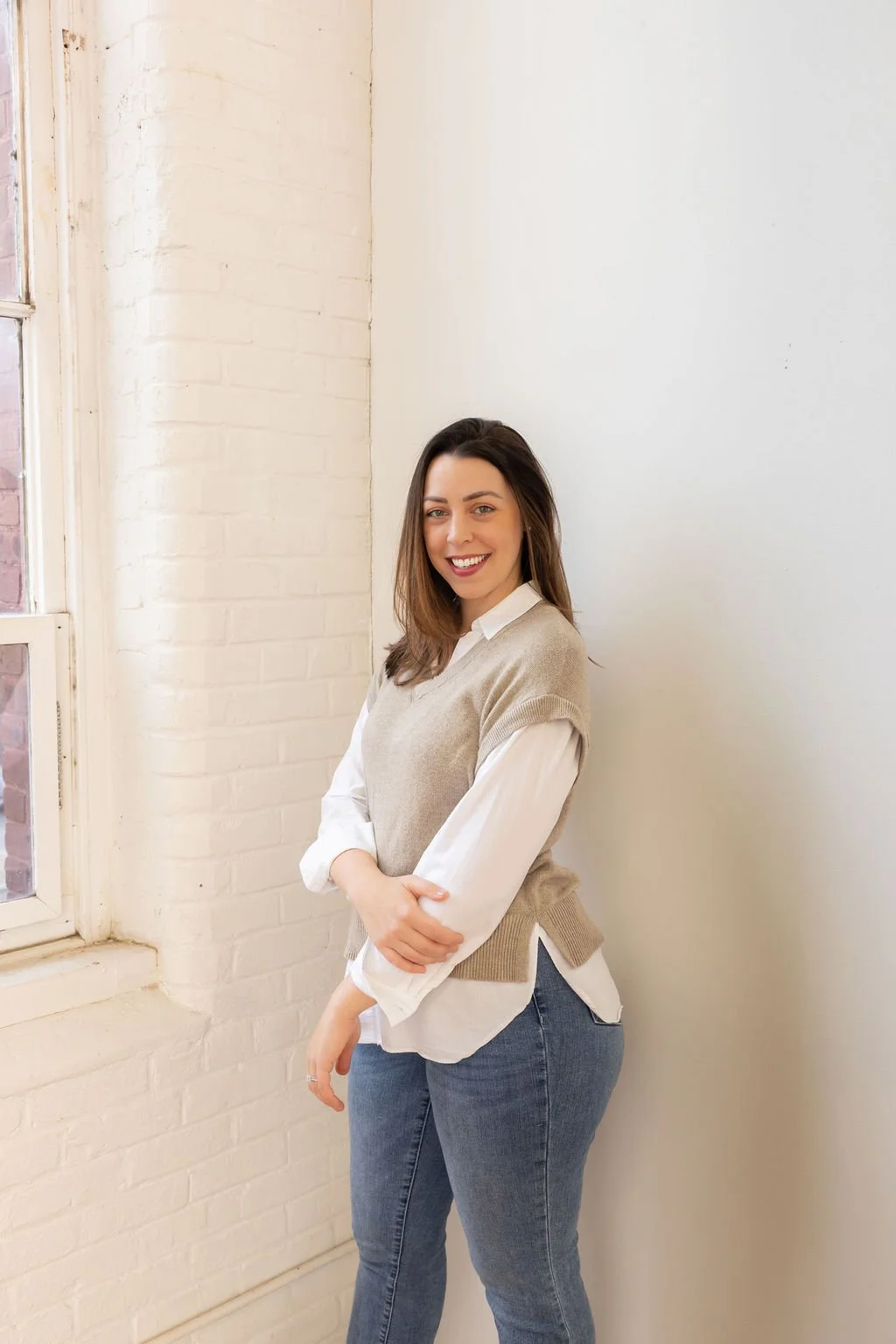 Kelly Martins Founder of GRATI Consulting Springfield Ma standing against a wall looking at the camera smiling