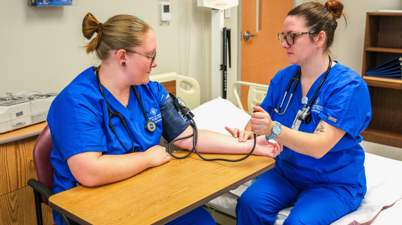 Nursing students practicing taking eeach other's blood presure