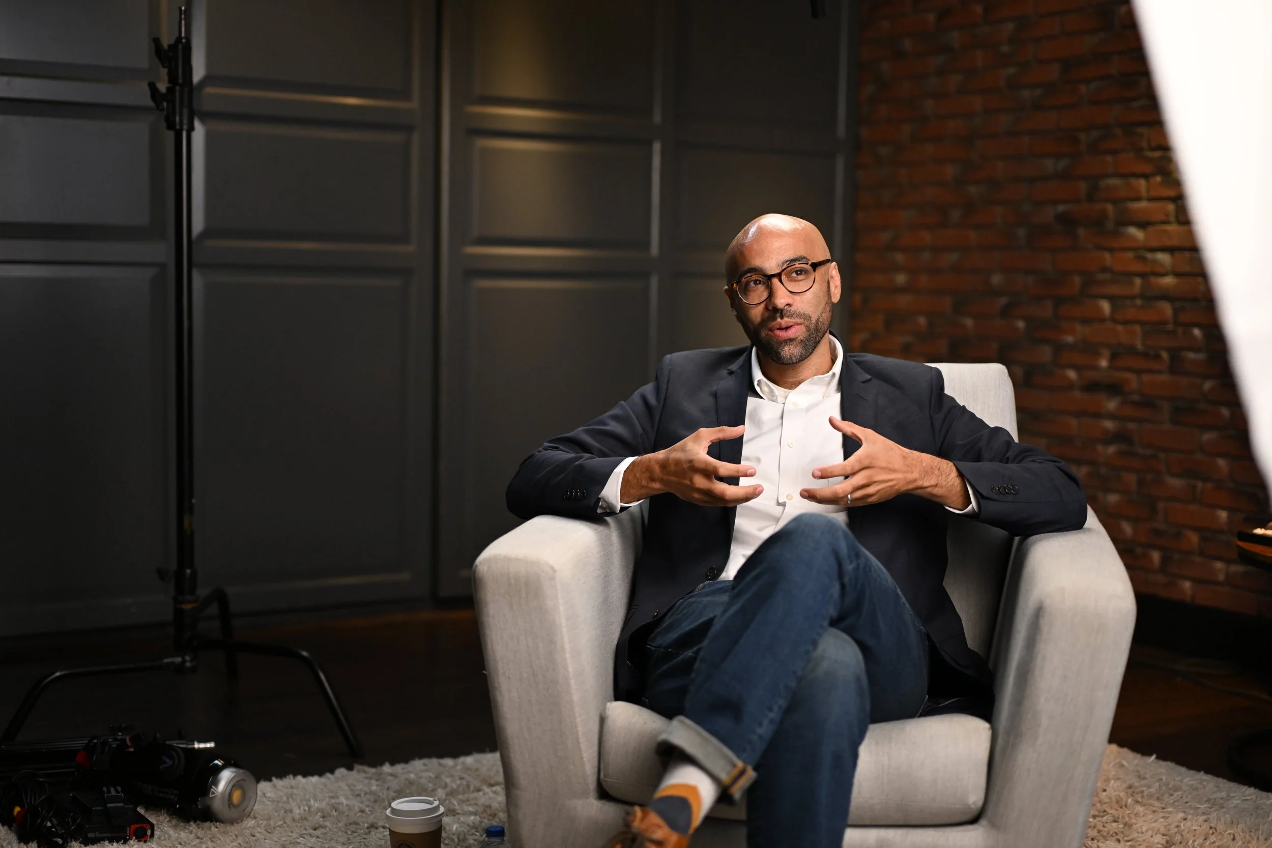A man with glasses, a beard, wearing a suit jacket and white shirt, sitting in a beige armchair  | Dr Matthew Breuninger | Therapist, Catholic Speaker, Course Creator, and Author | Steubenville, OH