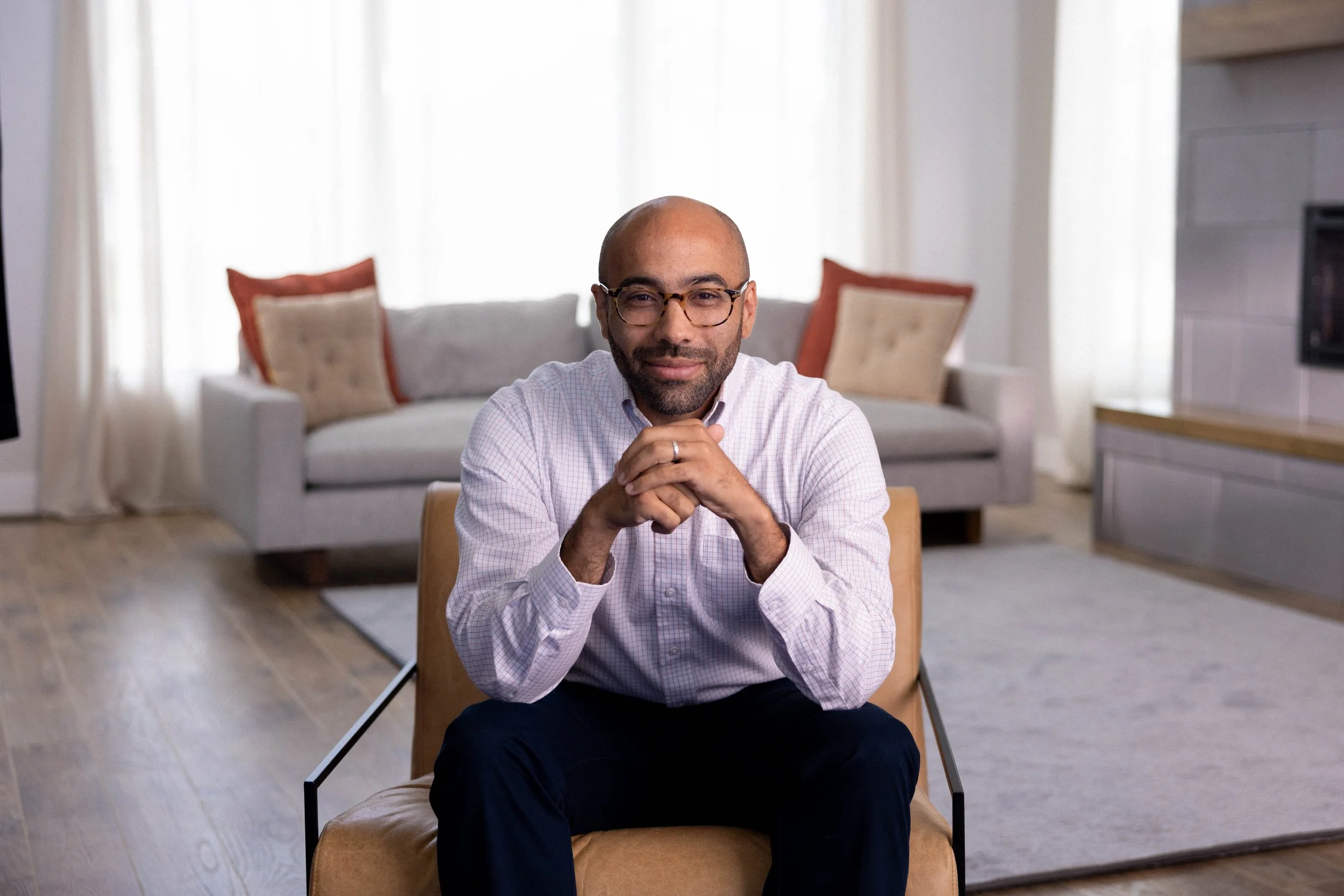 A man with glasses and a beard sitting on a chair in a living room  | Dr Matthew Breuninger | Therapist, Catholic Speaker, Course Creator, and Author | Steubenville, OH