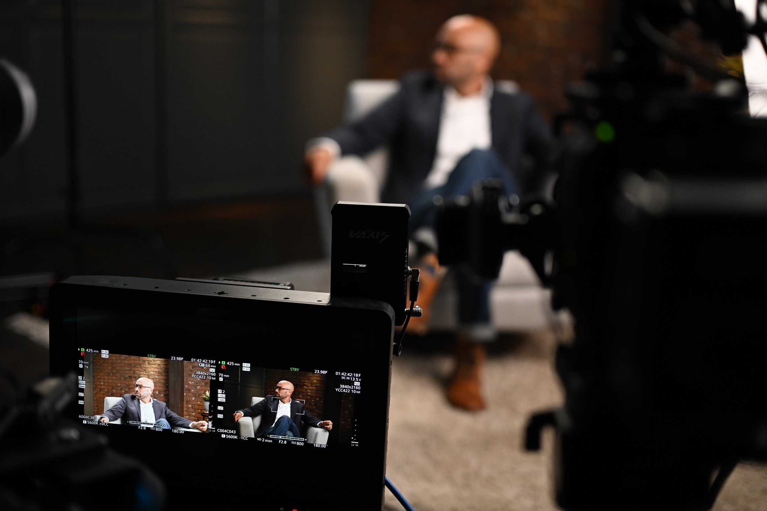 A video camera filming a man sitting on a white armchair  | Dr Matthew Breuninger | Therapist, Catholic Speaker, Course Creator, and Author | Steubenville, OH