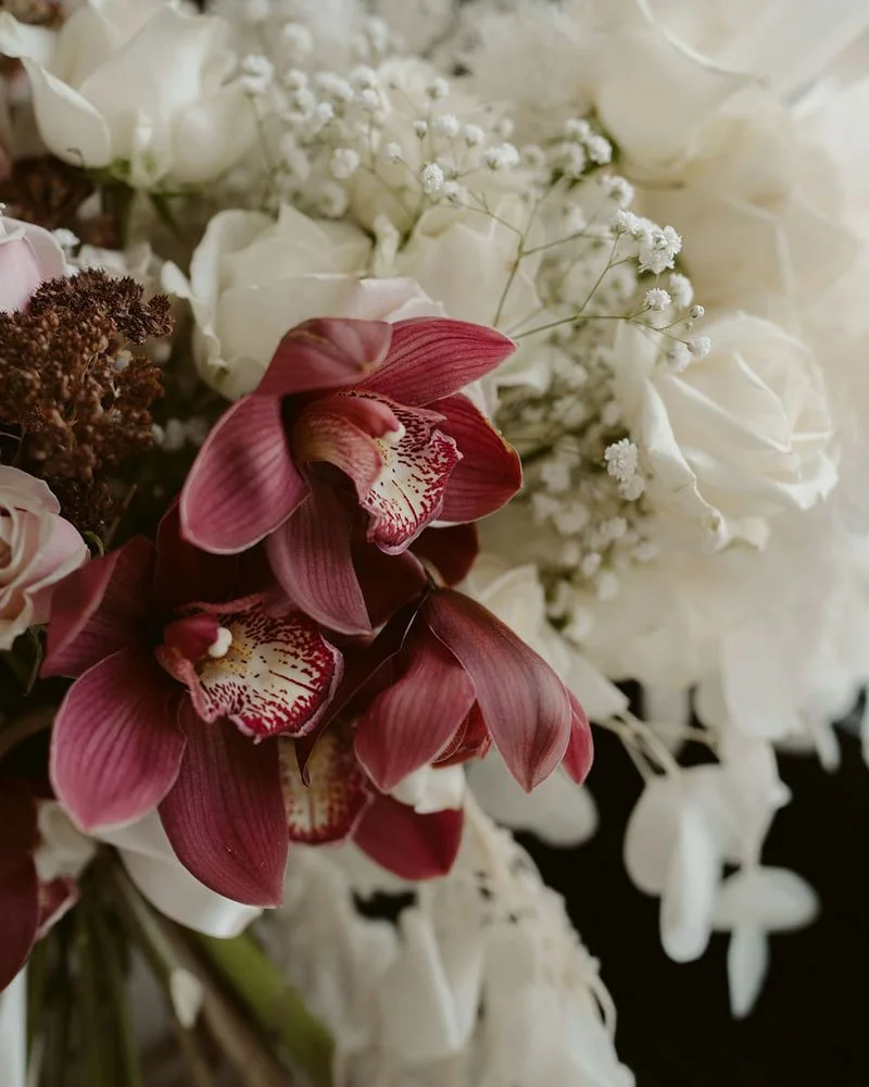 Close-up of a bouquet featuring pink orchids and white roses with baby's breath flowers.