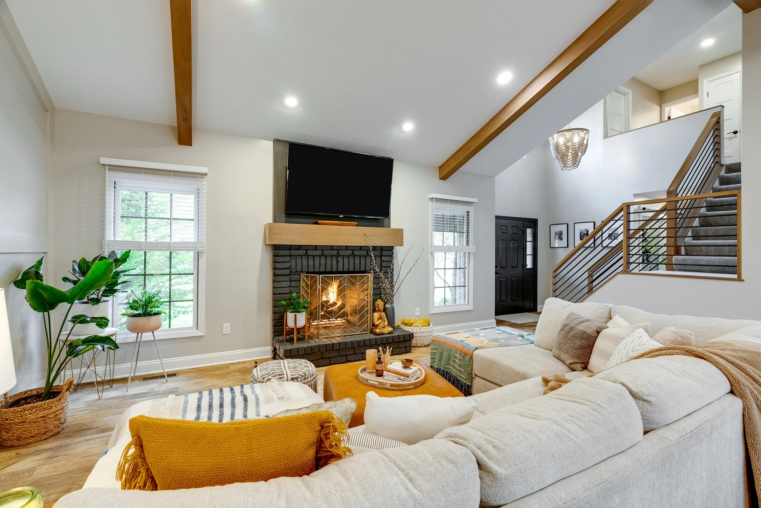 Modern bathroom with a white freestanding bathtub, black fixtures, black vanity with a mirror, black shower with glass enclosure, white cabinets, black countertop, black window blind, and white marble floor tiles.