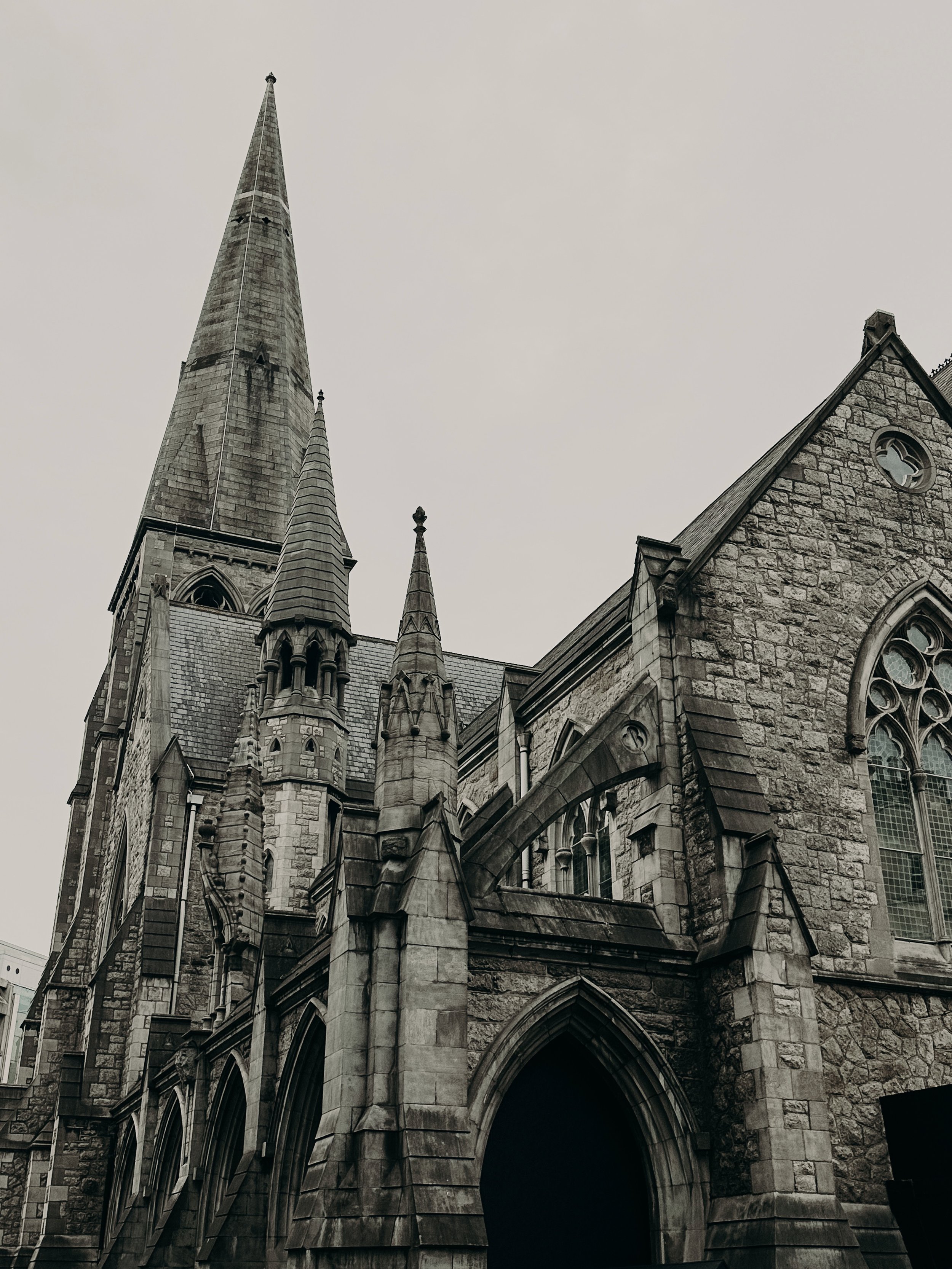 A black-and-white photo of a Gothic-style church with pointed spires, arched windows, and stone walls.