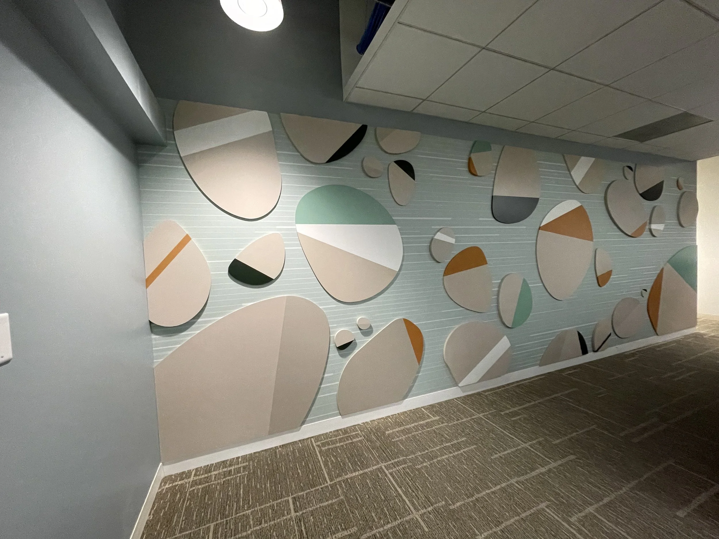 Installed rock-themed wallcovering with layered dimensional Sintra stone elements in Amazon SJC3 corridor, fabricated and installed by JP Digital in Cupertino, California.