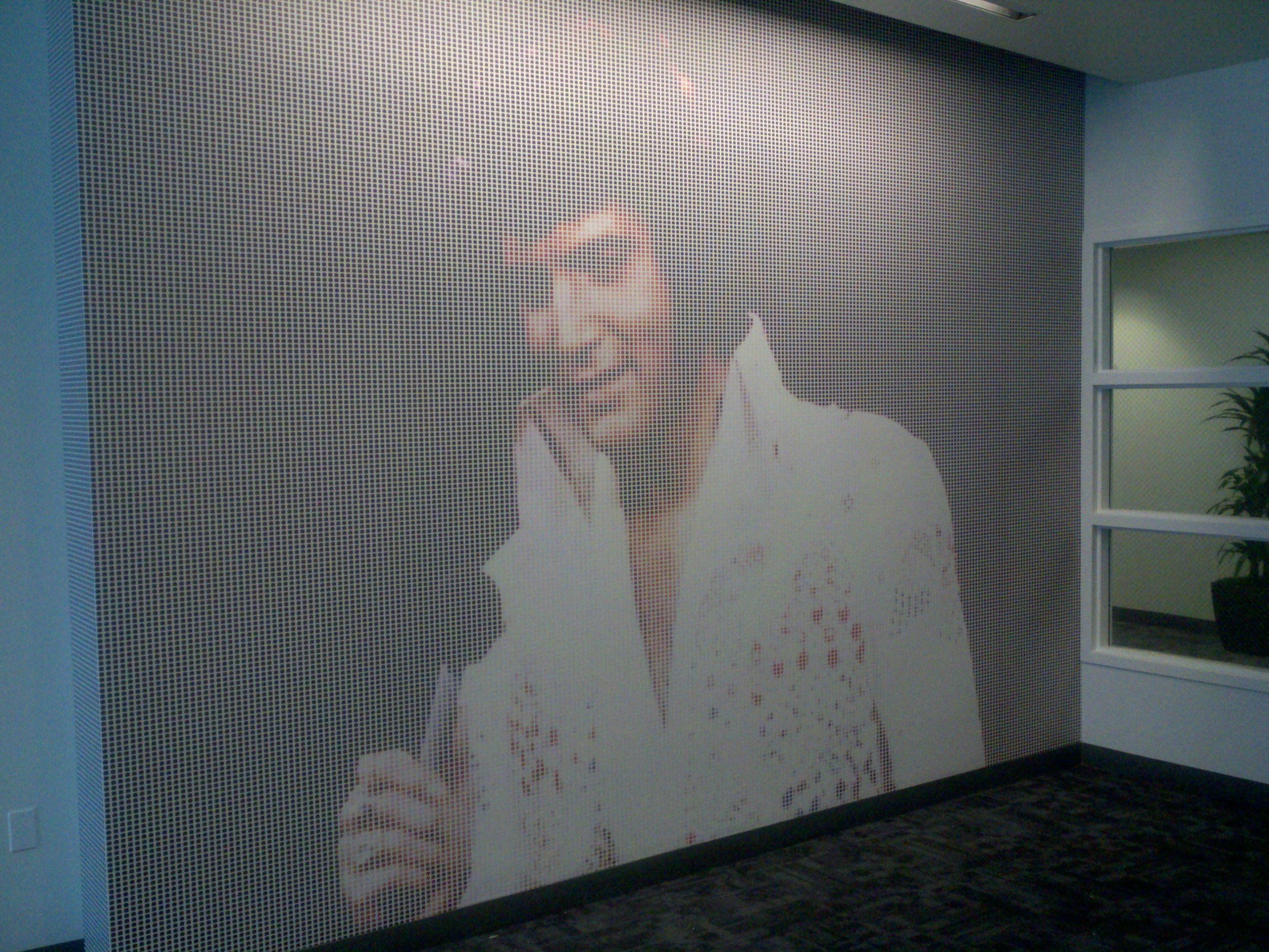Branded portrait-style environmental graphic installed as a large-scale office feature wall.