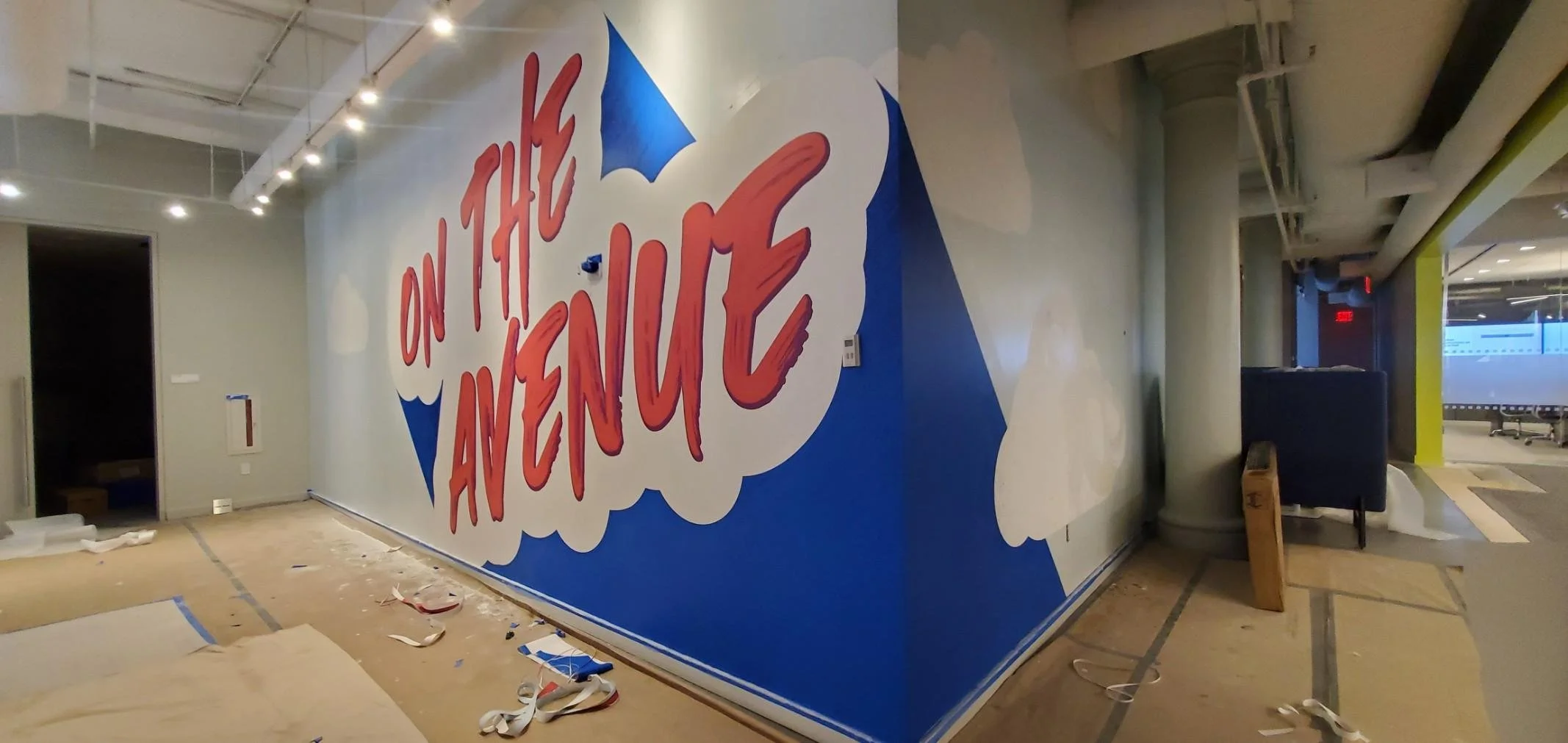 Wallcovering installation in progress at eBay New York office featuring large “On the Avenue” environmental graphic mural during workplace branding installation