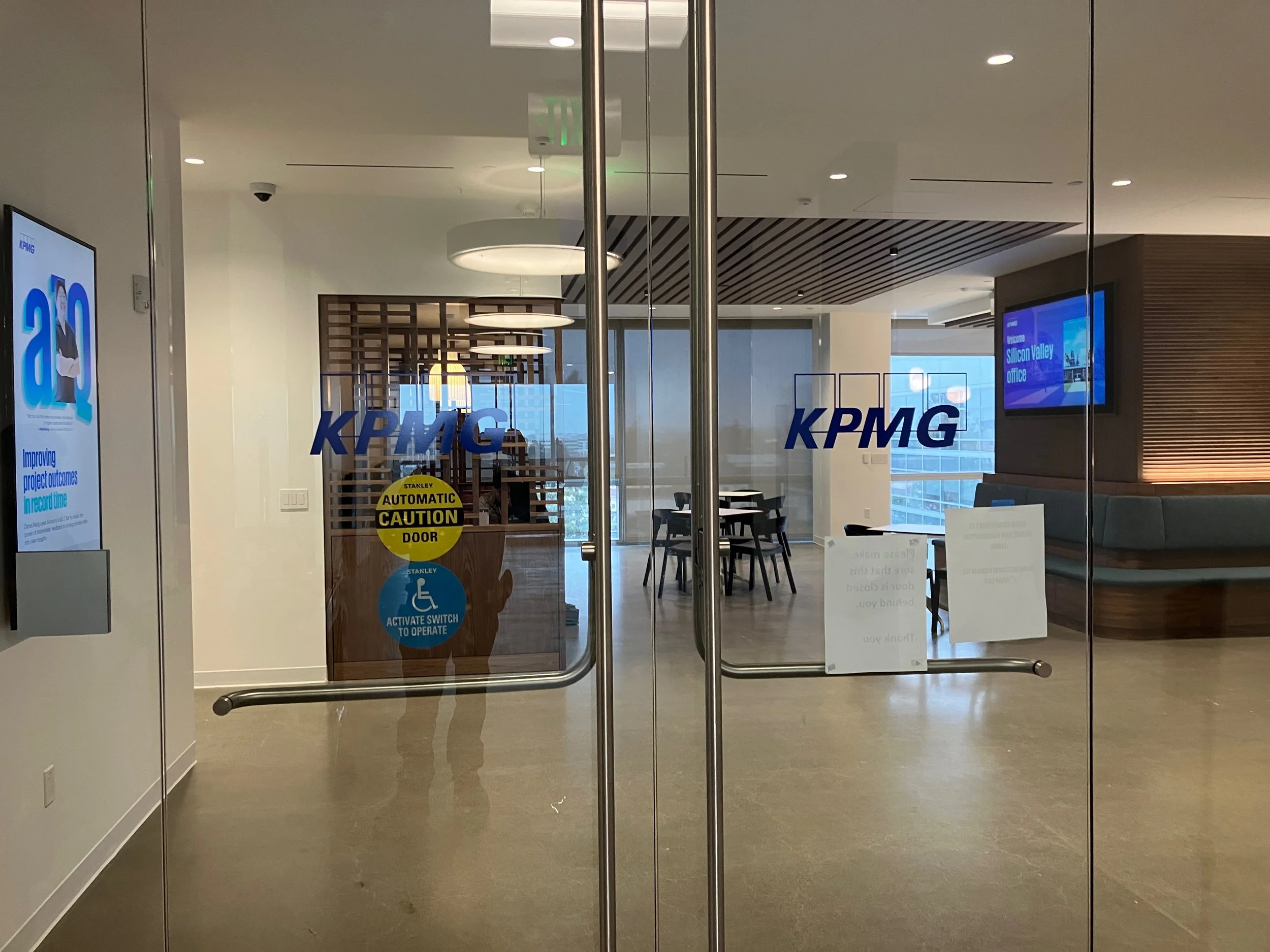 Branded KPMG logo vinyl applied to glass entry doors at the KPMG San Jose office for corporate environmental branding.