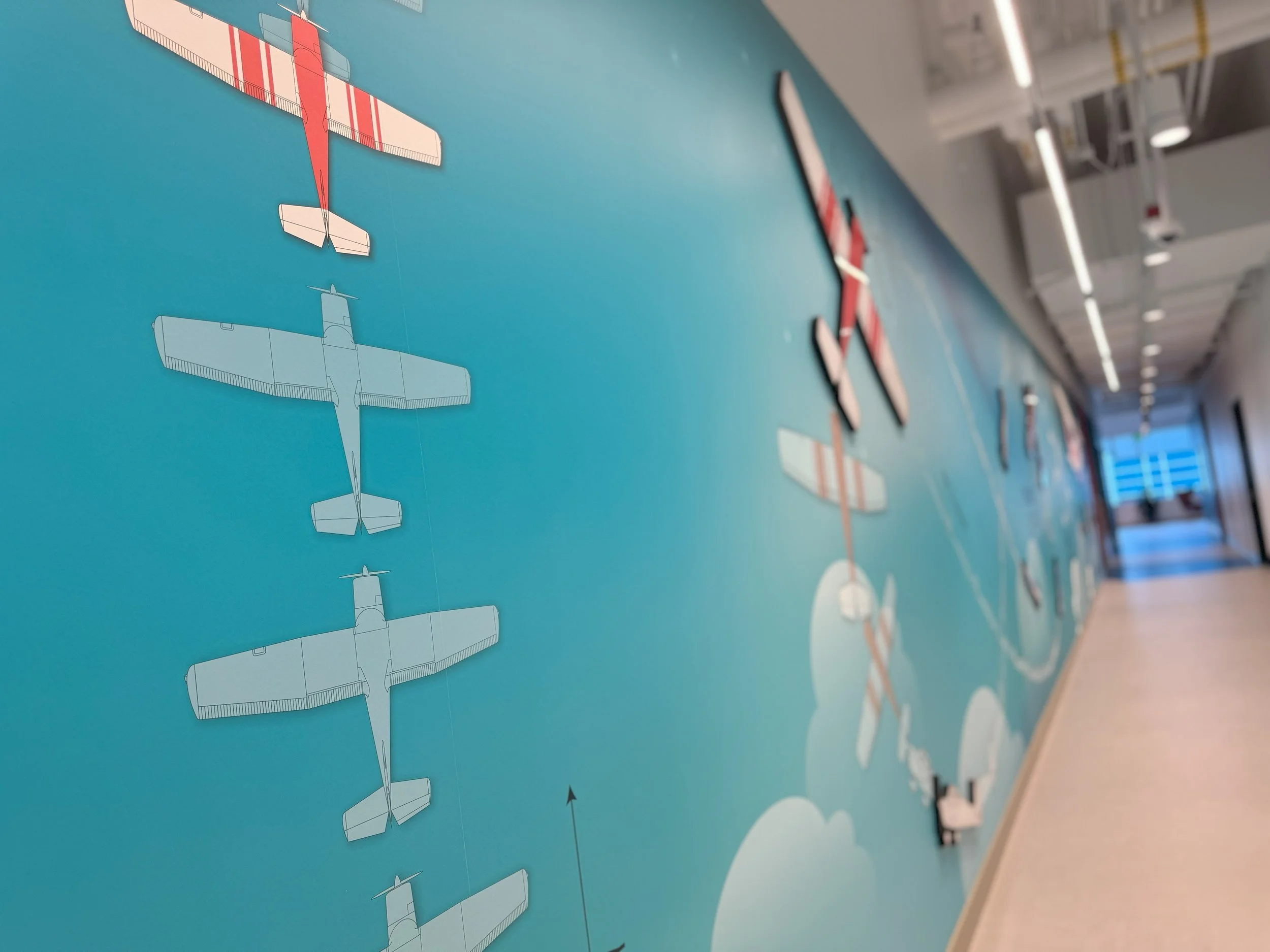 Directional environmental wall graphics with integrated typography to support intuitive workplace navigation.
