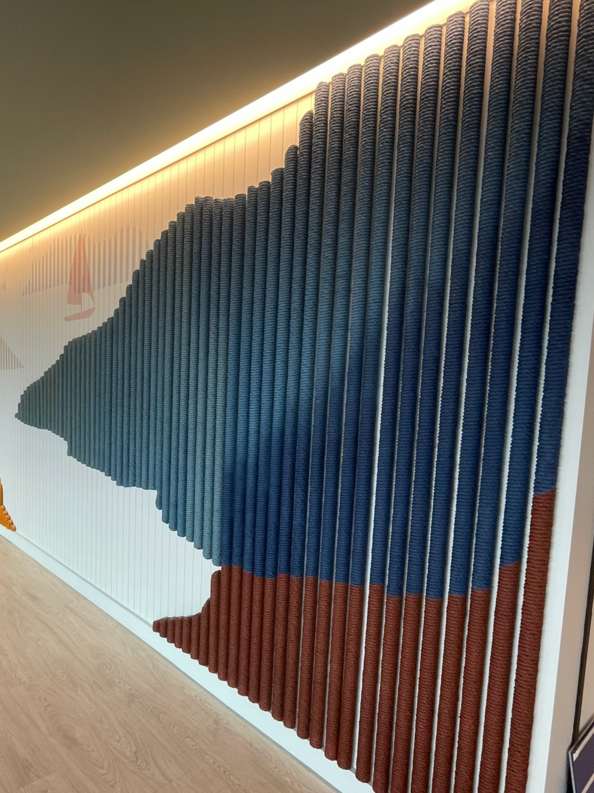 Custom rope-texture wallcovering installation forming a dimensional acoustic feature wall with layered color design for enhanced sound absorption and visual impact in a commercial interior.