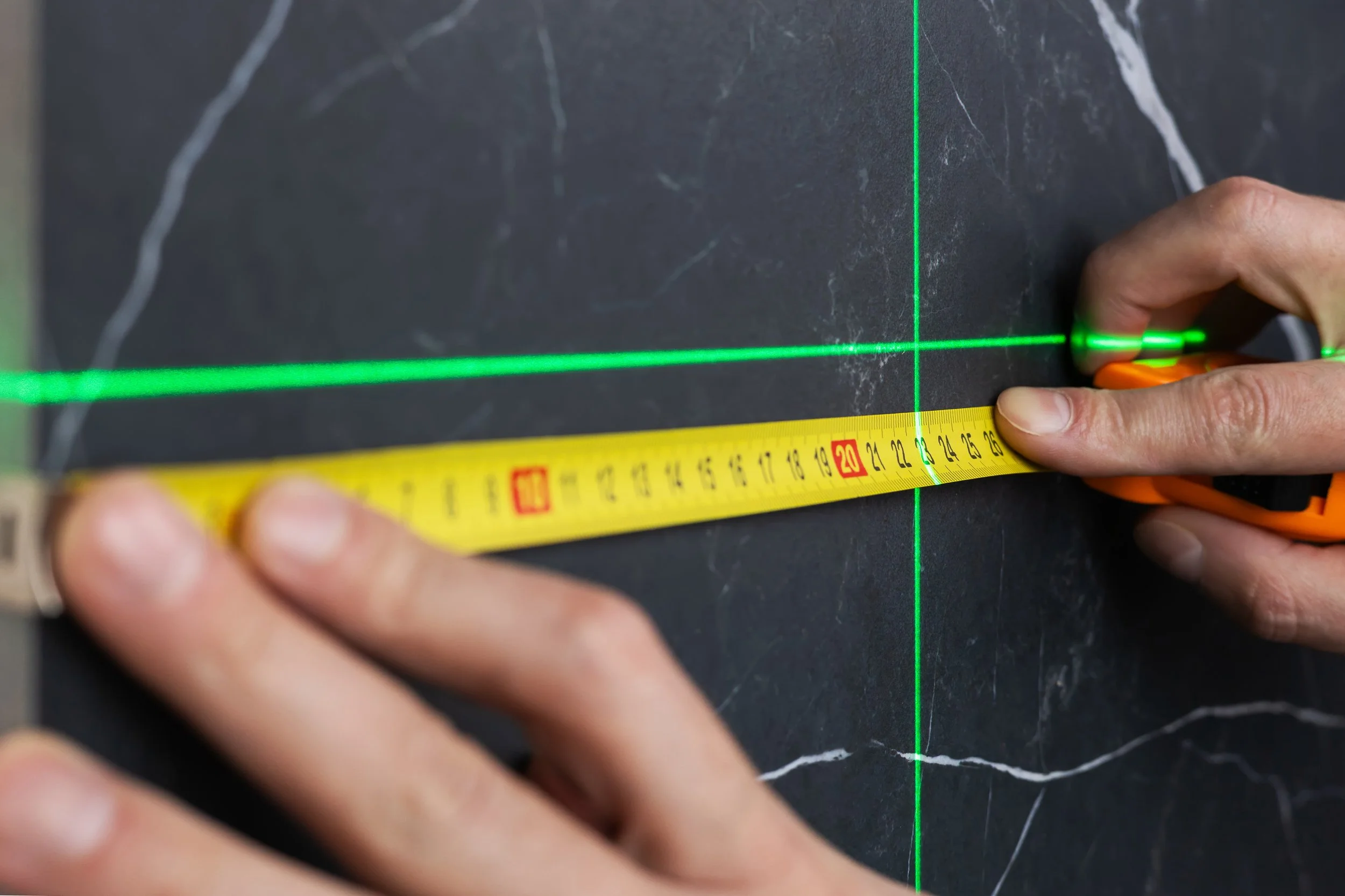 Technician measuring wall surface for commercial site and architectural graphics installation during site survey and project planning