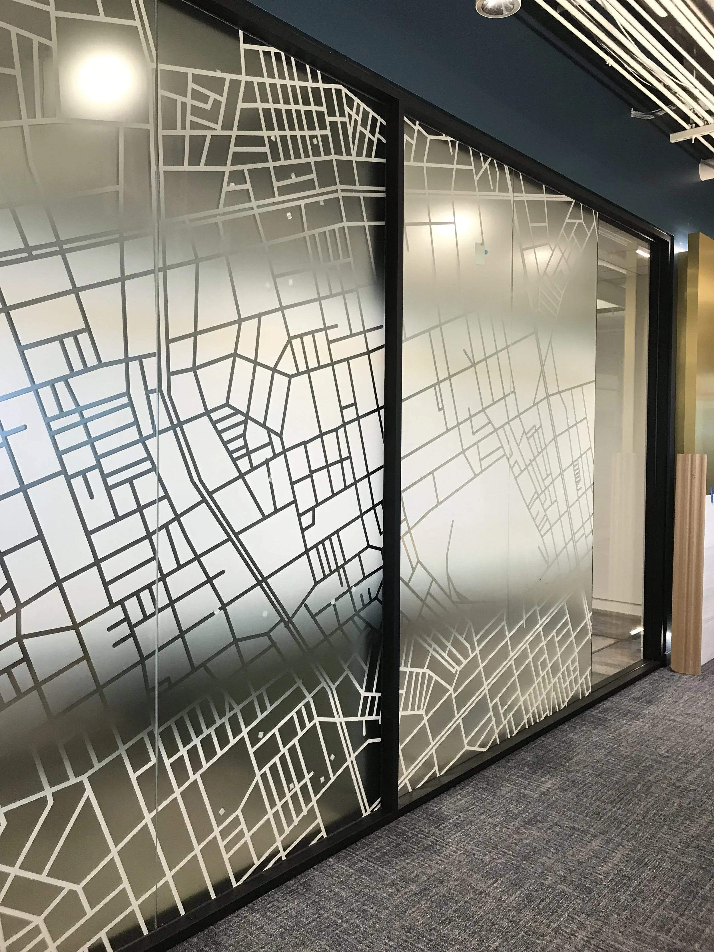 Commercial privacy window film with custom architectural pattern installed on office glass for decorative privacy and light control.
