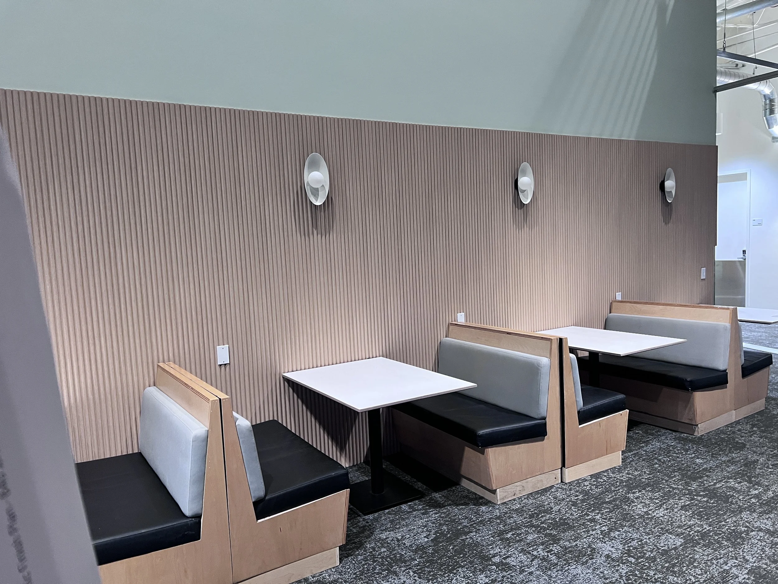 Architectural wood slat wall paneling installed in a commercial seating area, adding natural texture, warmth, and modern interior design appeal.