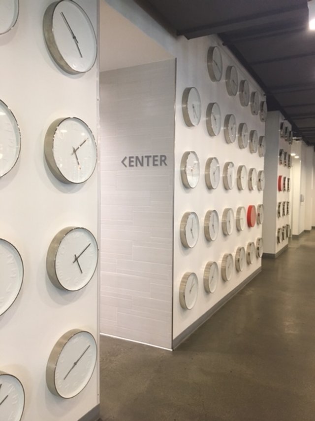 Custom dimensional environmental graphics featuring multi-clock installation creating a branded experiential feature wall in corporate office