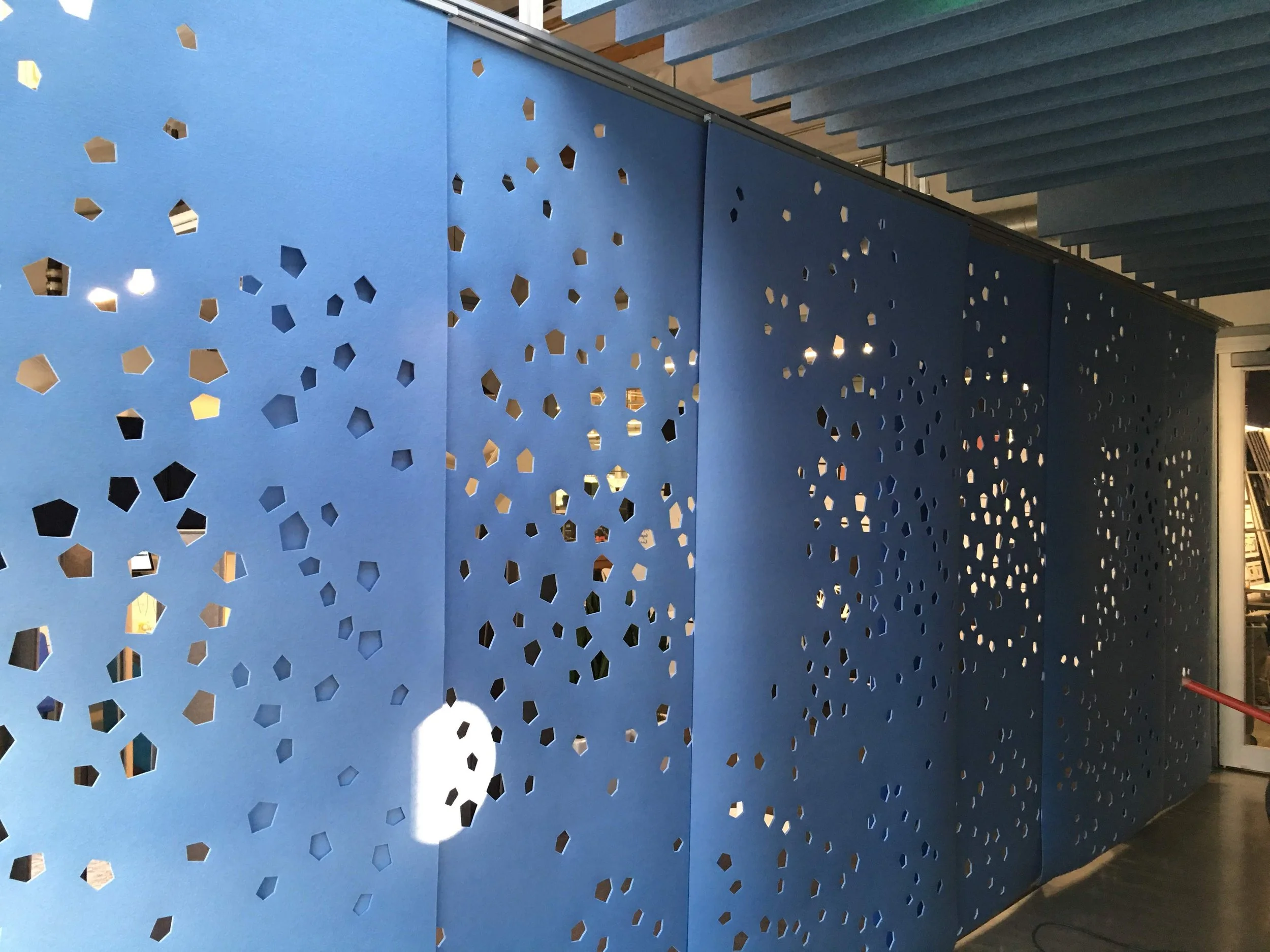 Decorative perforated acoustic wall providing visual interest and sound absorption in office