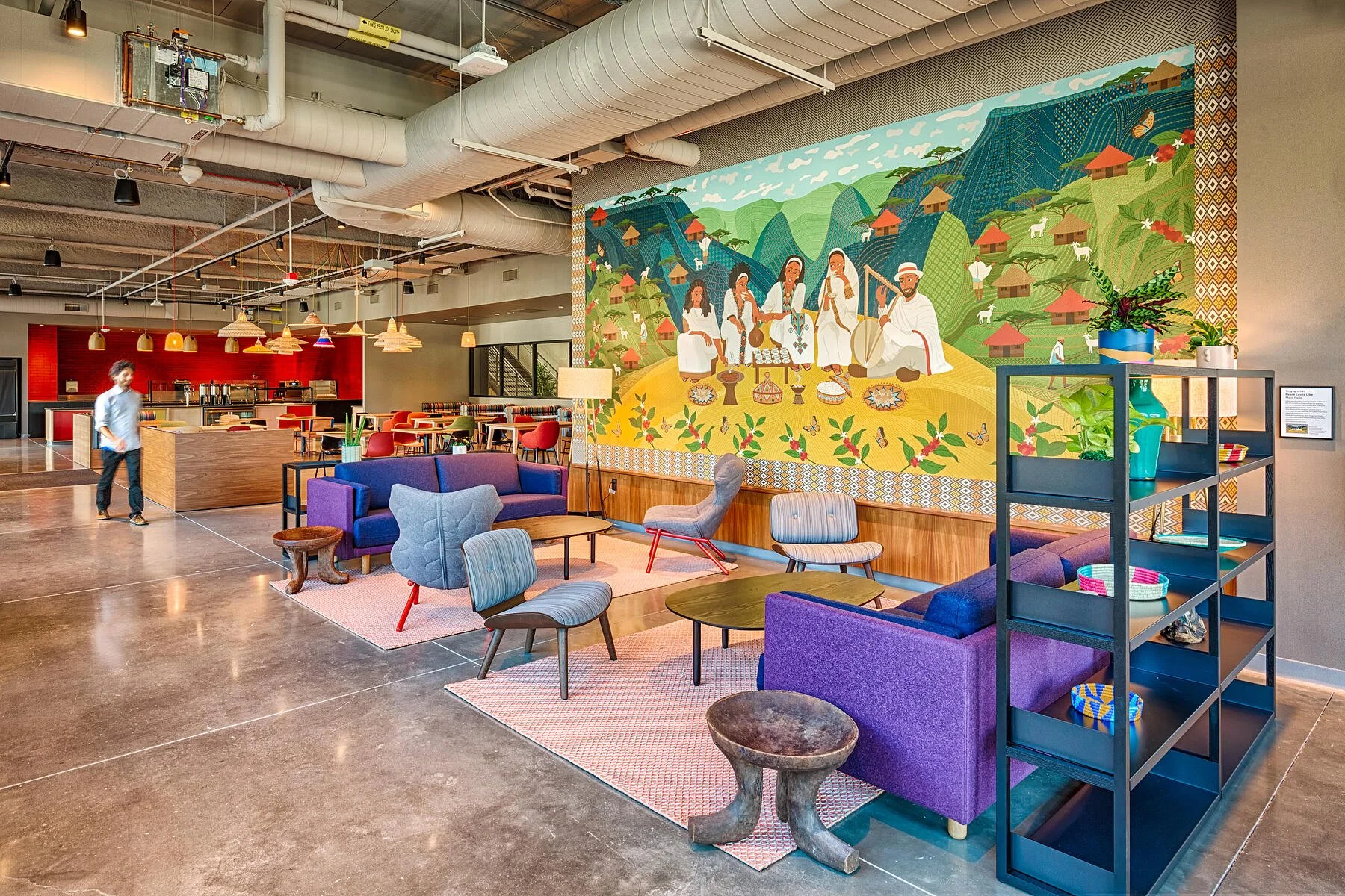 Modern office lounge featuring large-scale cultural illustrated wall mural and custom environmental graphics within a collaborative commercial workspace