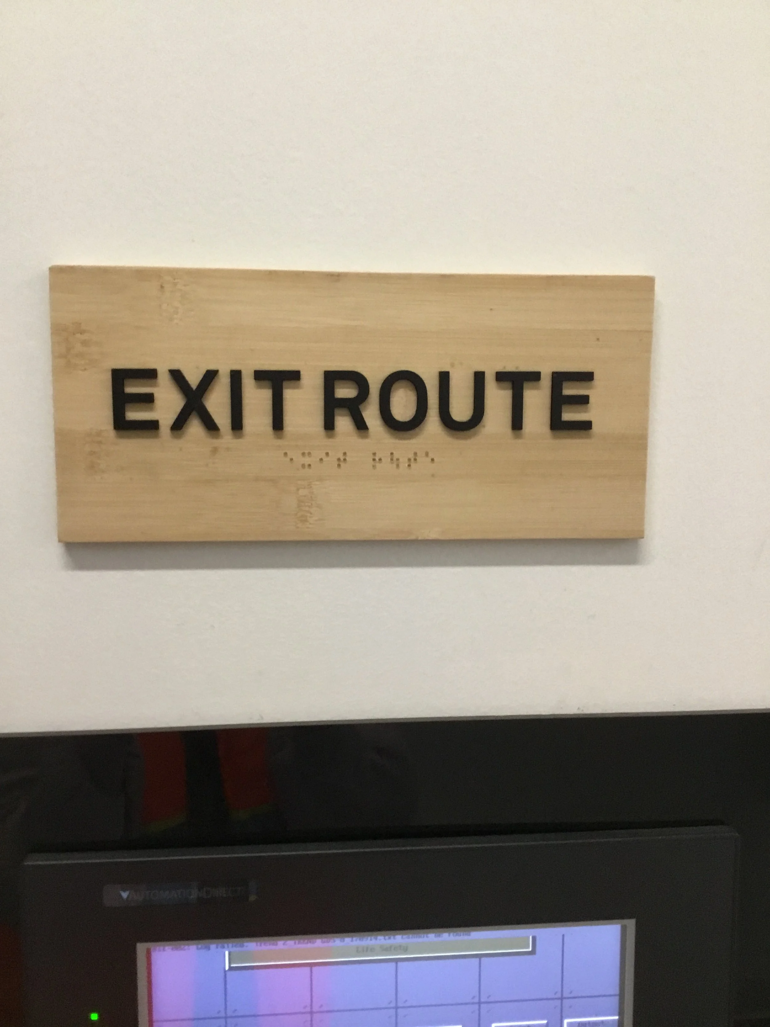 Exit route tactile signage with braille installed to support safety compliance and accessible navigation in commercial building