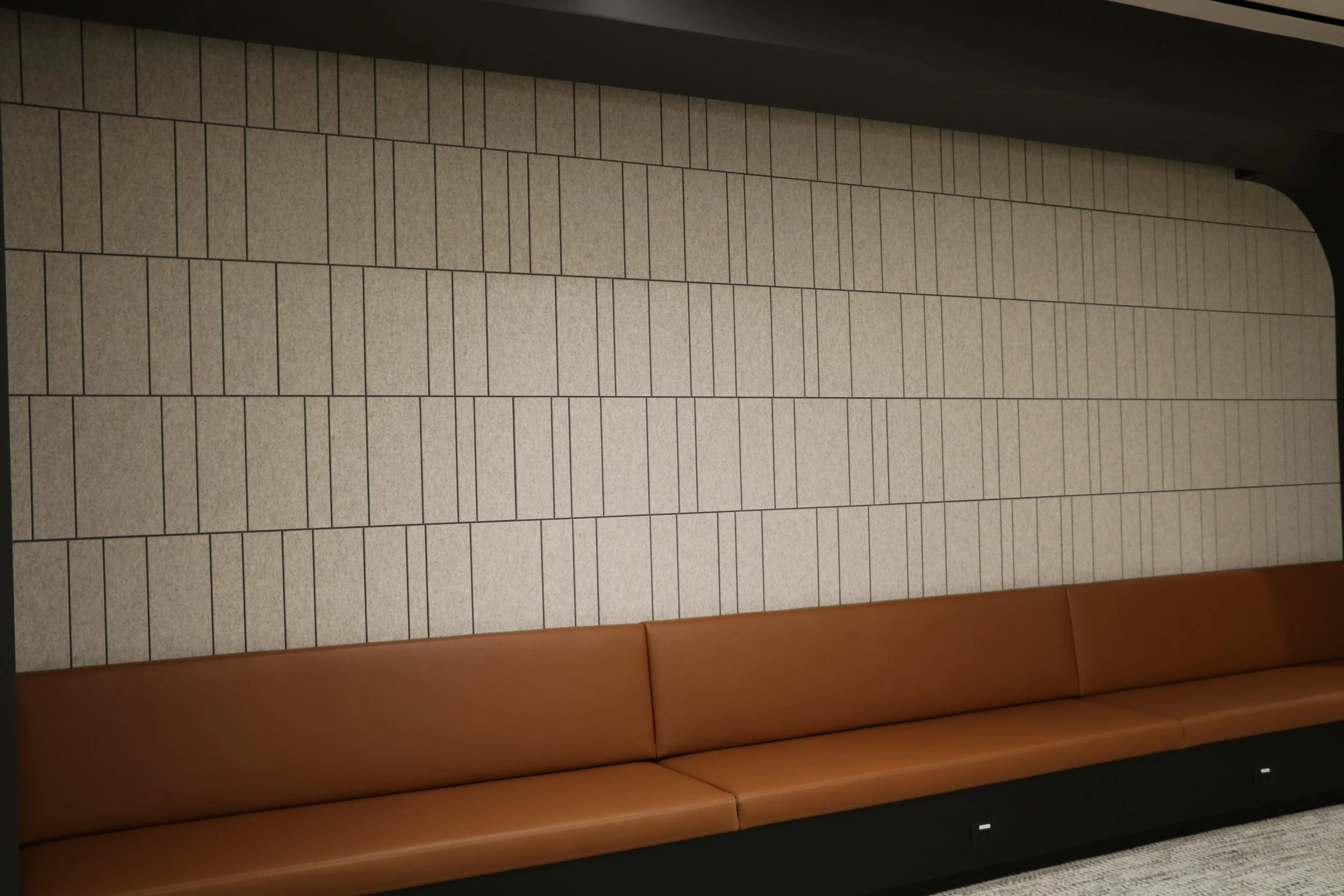 Acoufelt Fracture Barcode acoustic wall panels in Quartz installed behind built-in seating to improve sound absorption in commercial lounge area.