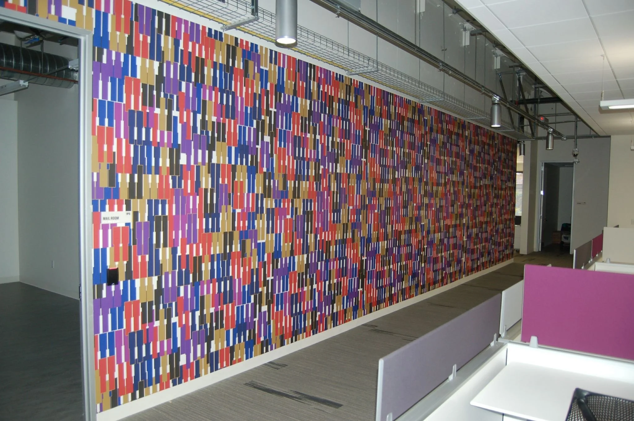 Multicolor geometric environmental graphic creating a high-impact feature wall in a commercial interior.