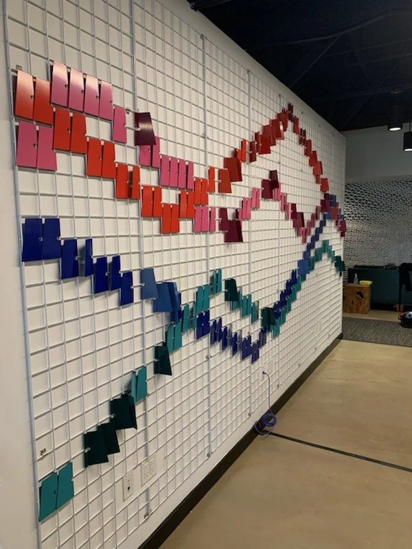 Custom geometric wall installation adding texture, movement, and brand storytelling throughout the workspace.