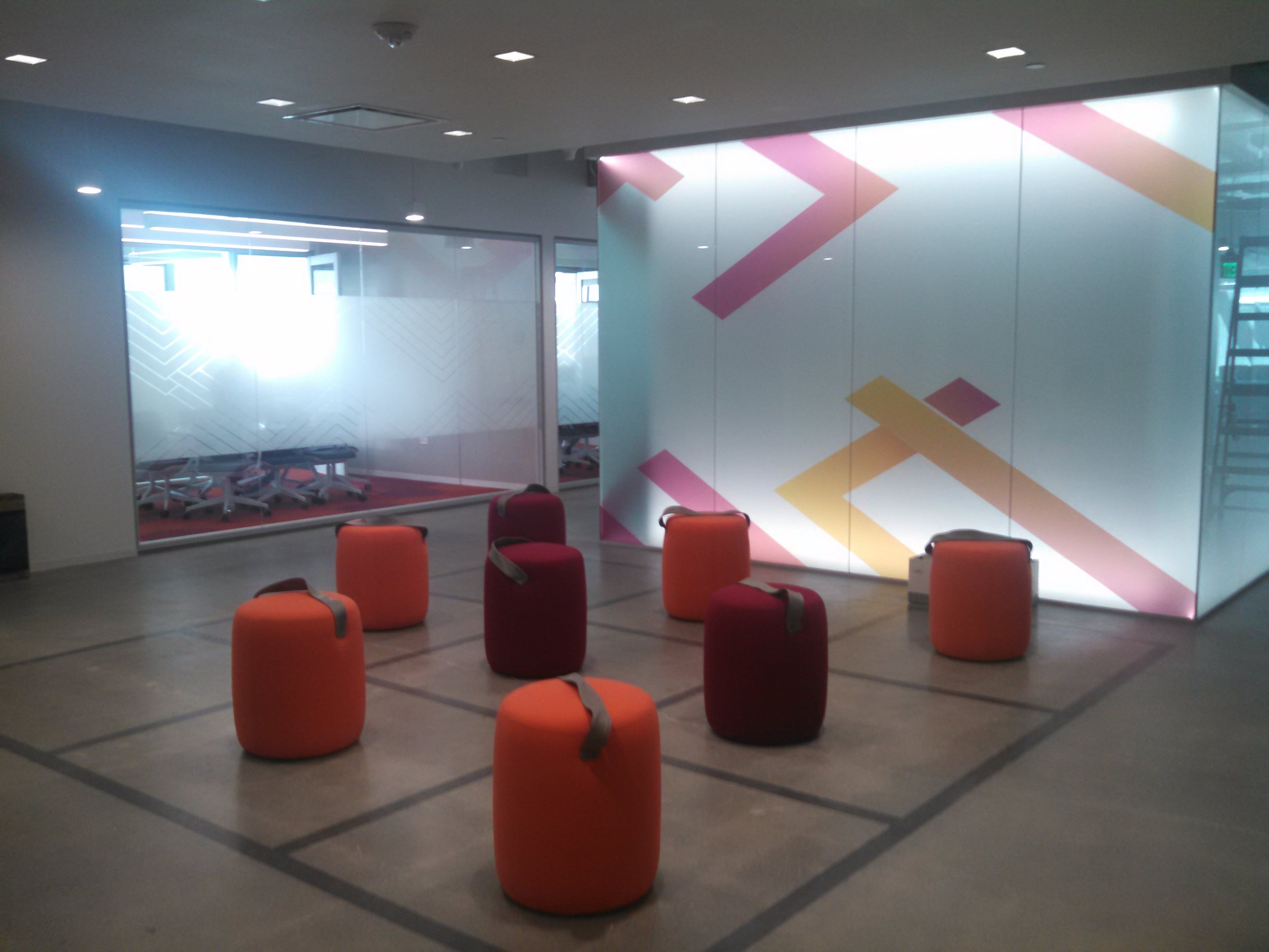 Custom decorative window film with geometric graphics applied to glass walls for branded office design and privacy.