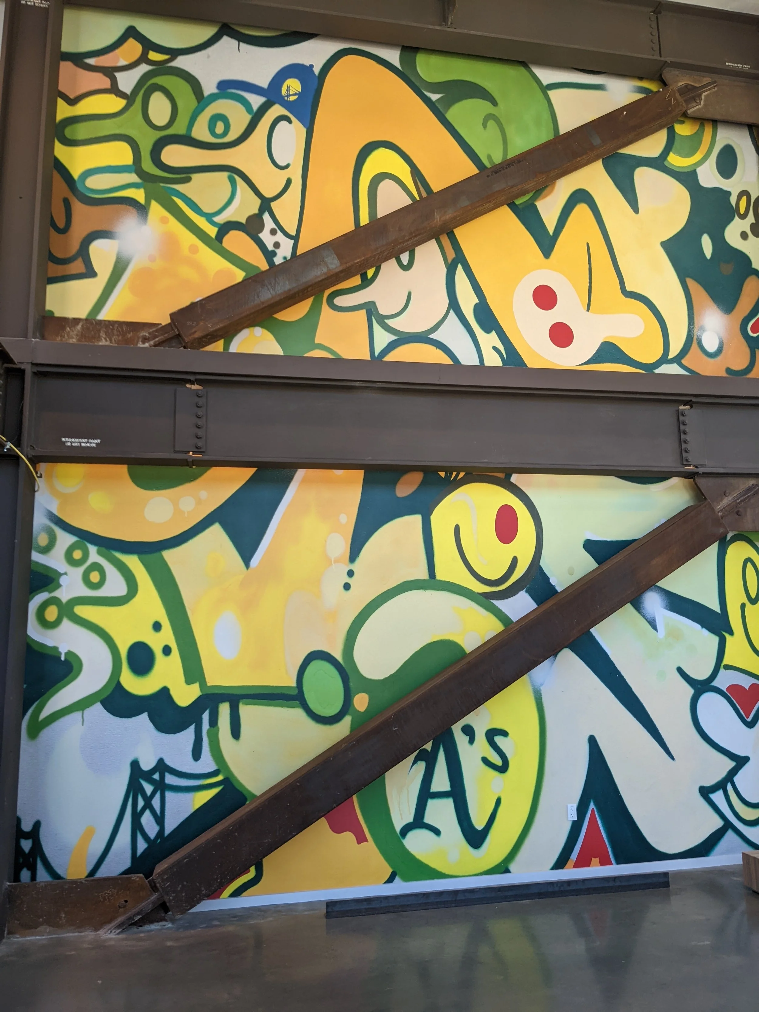 Custom illustrated wallcovering mural installed in a commercial hospitality area with exposed structure and integrated environmental graphics