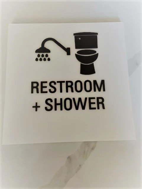 ADA-compliant restroom and shower signage with tactile symbols and braille for accessible navigation in commercial facility