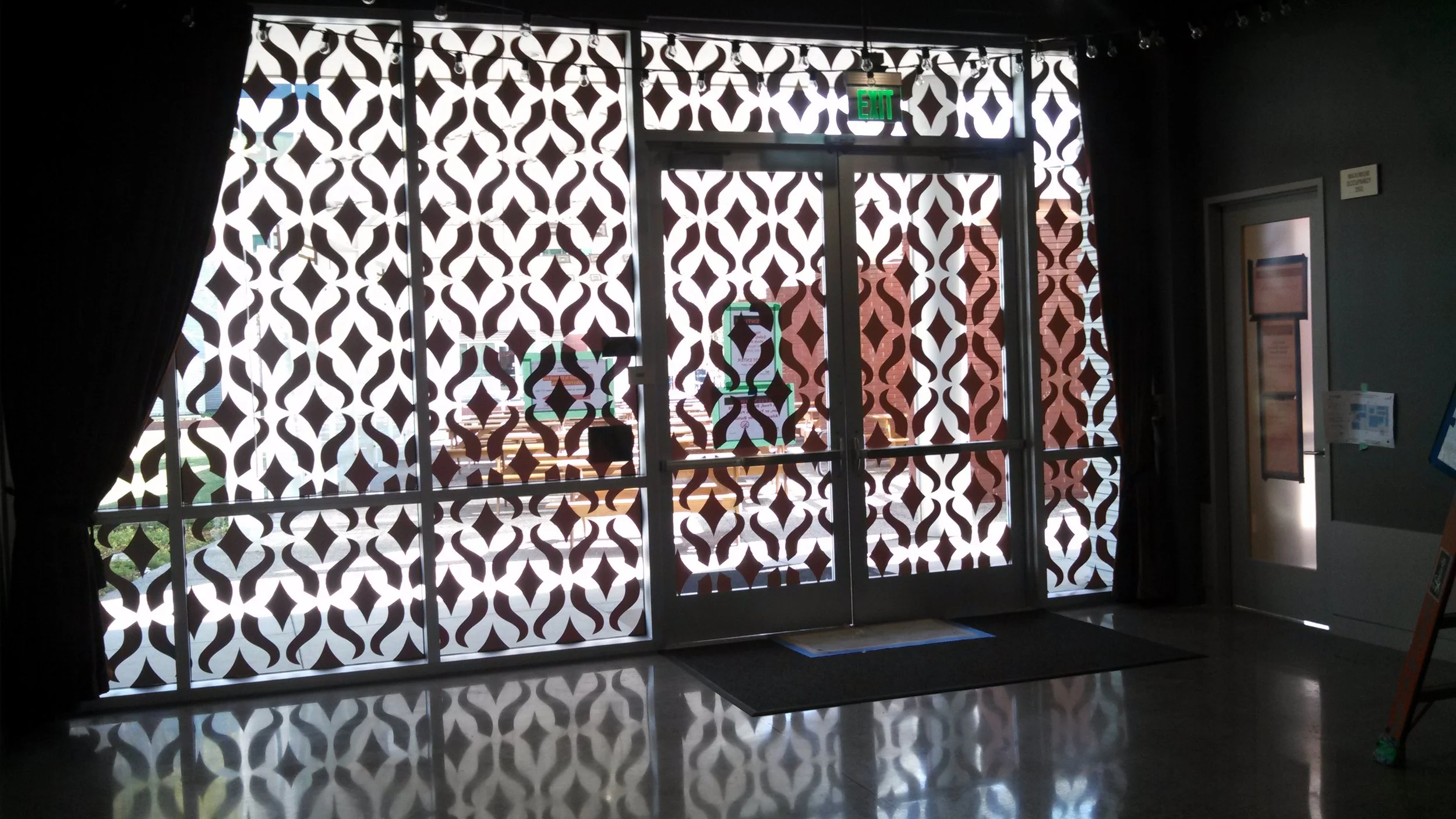 Decorative patterned window film with custom cut design for privacy and branding on interior glass partitions.