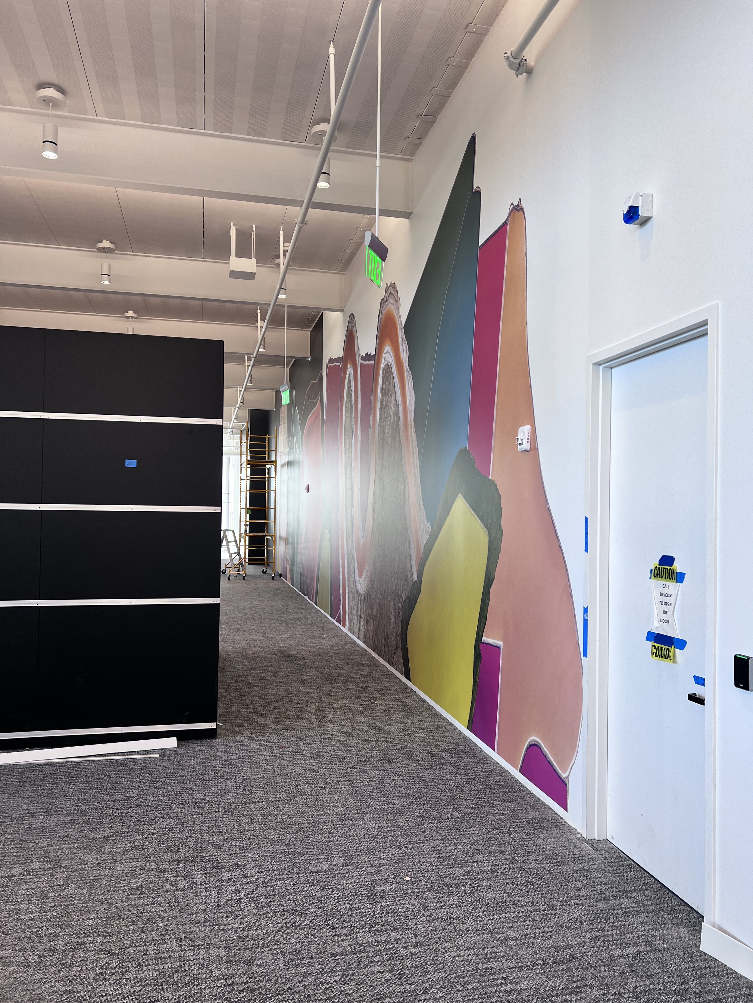Colorful geometric environmental graphics wall adding bold visual branding to a workplace hallway.