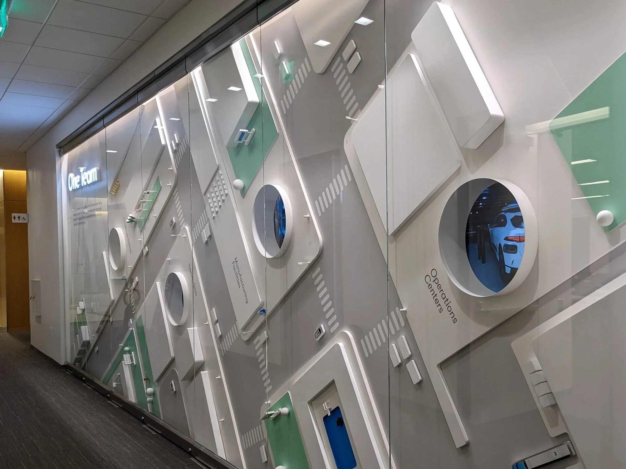 Custom architectural feature wall with dimensional panels and integrated lighting installed in a commercial office environment by JP Digital.