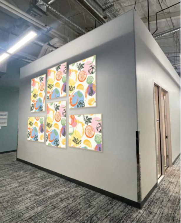 Framed wallcovering panel installation in amphitheatre hallway featuring colorful fruit pattern artwork arranged in a grid on a corner wall.