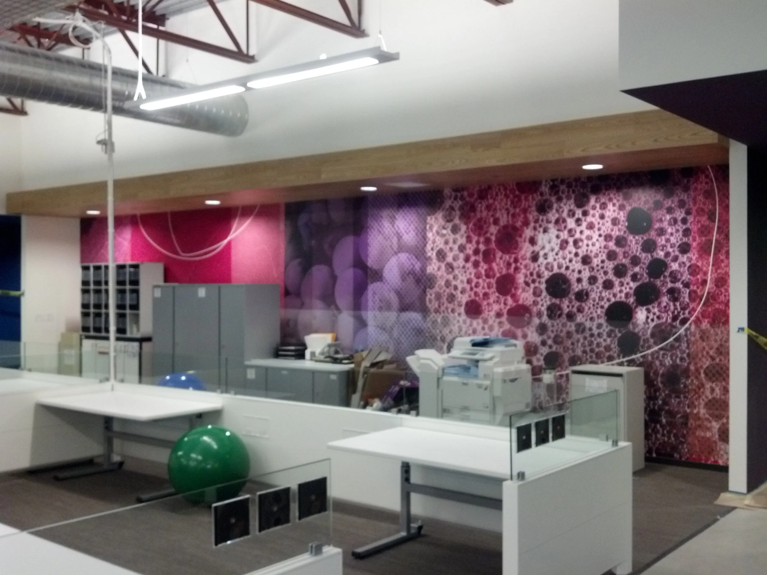 Custom wallcovering installed in a modern office lounge to create a vibrant branded environment.