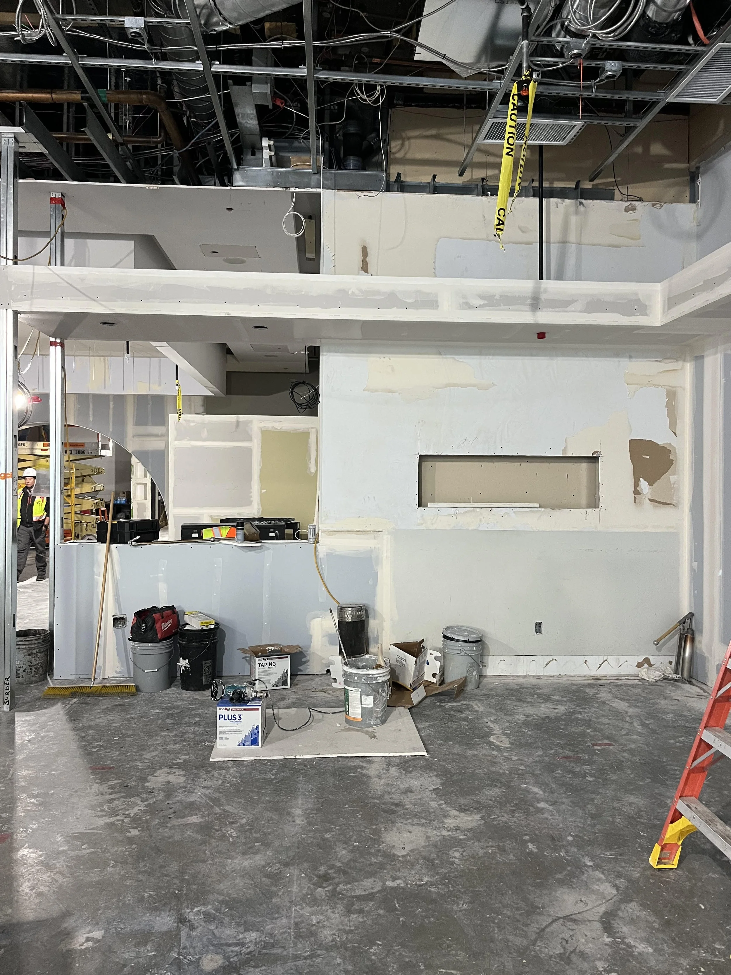 Interior construction site showing drywall preparation and recessed wall niche installation for future architectural signage or display.