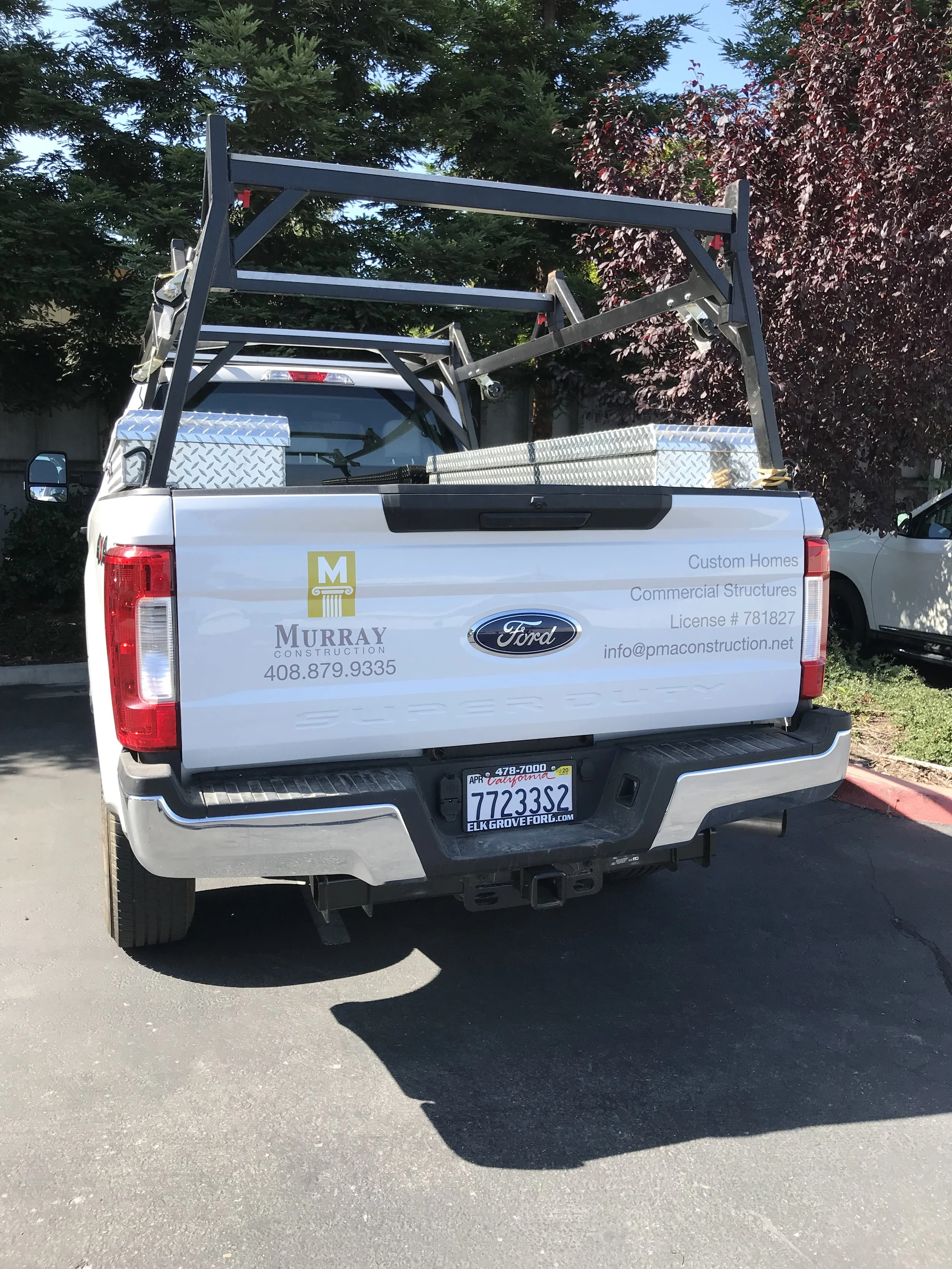White Chevrolet service truck with company logo and contact information applied as commercial vehicle graphics, parked outdoors.