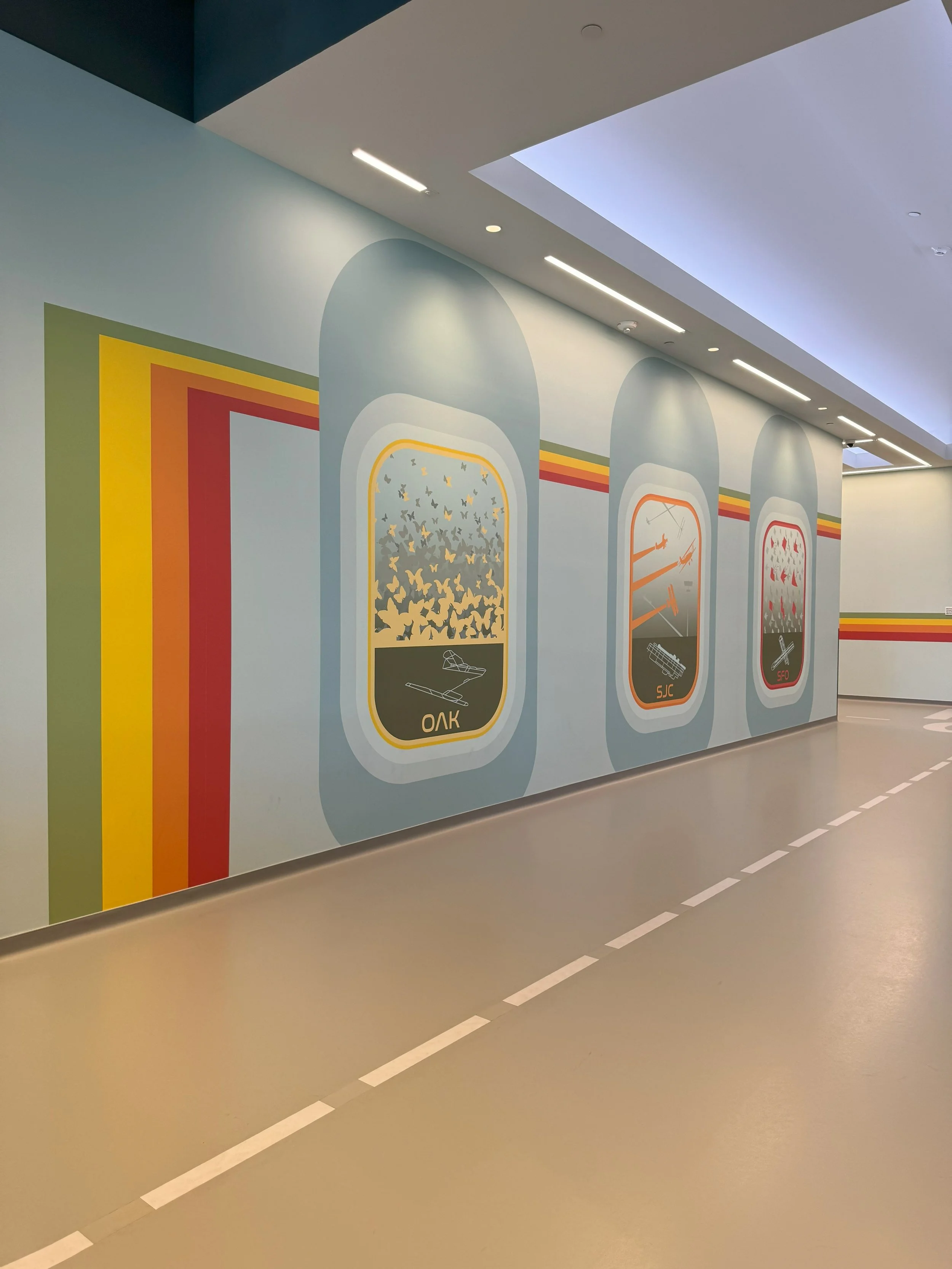 Large-scale environmental graphics and color-coded door system designed to support intuitive wayfinding in a corporate corridor.
